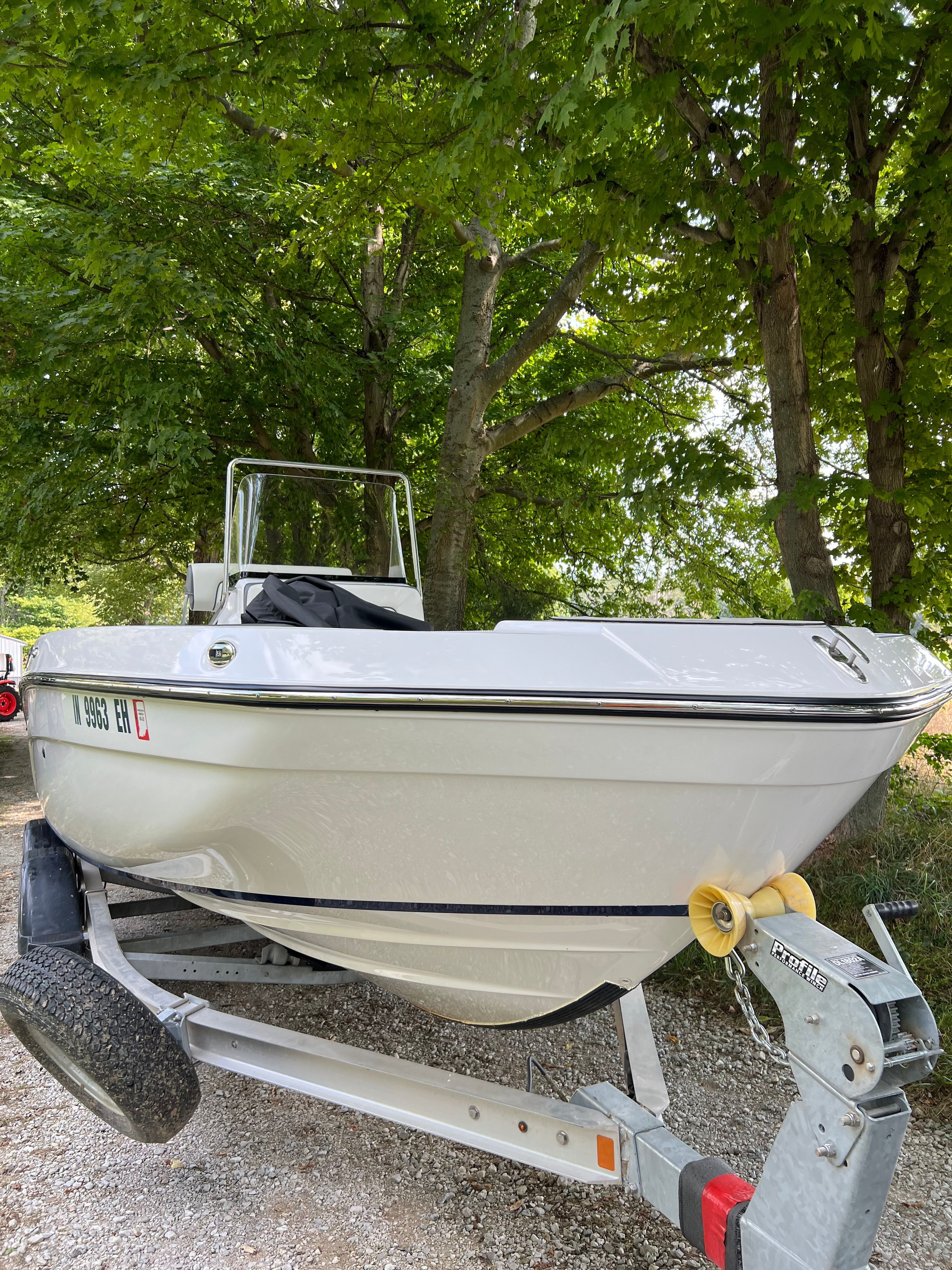 2022 Yamaha Boats 210 FSH Deluxe on trailer in a wooded area.