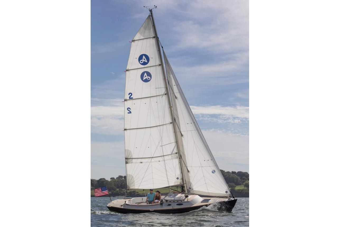 2015 Alerion Sport 30 sailboat on open water, clear sky, American flag.