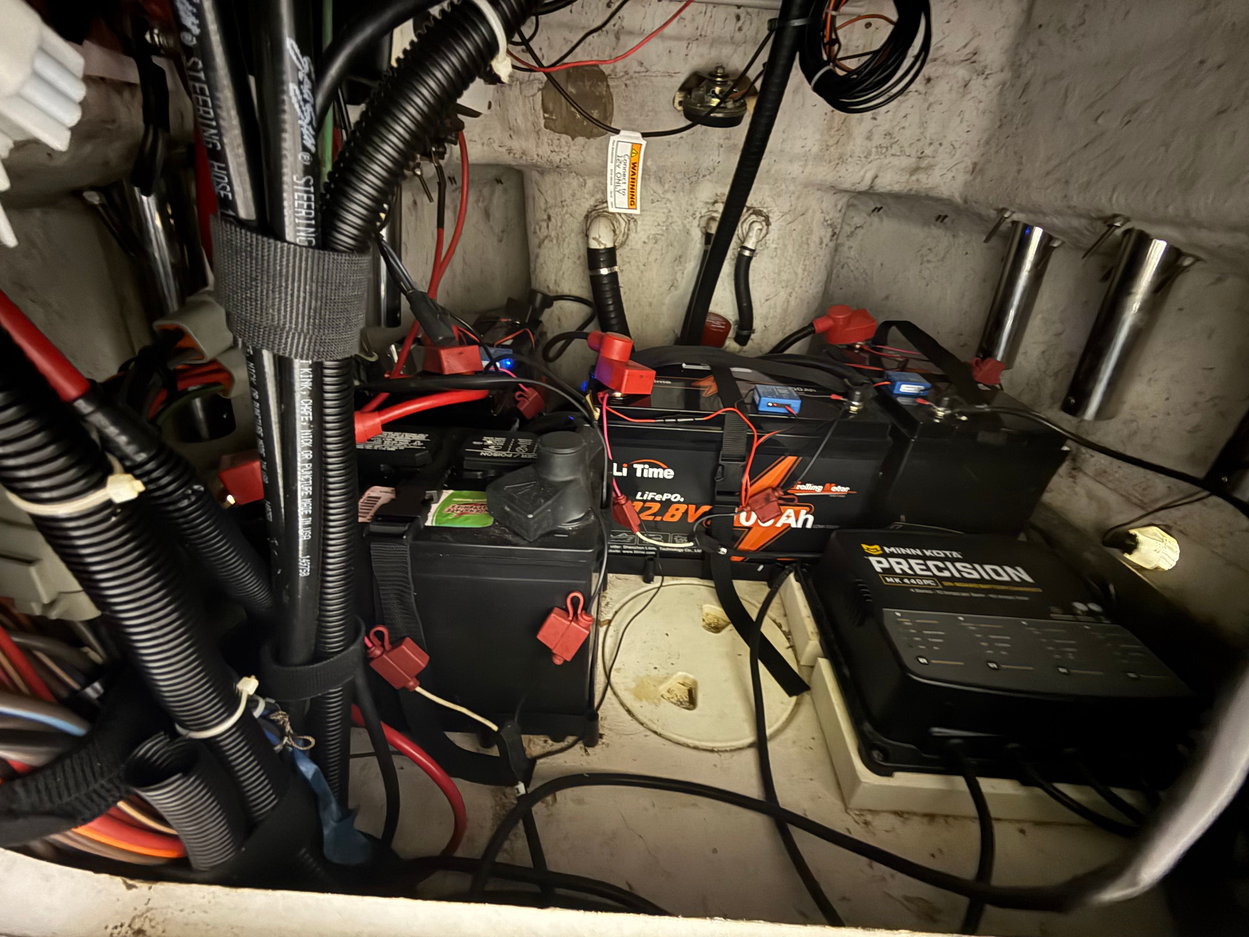 Batteries and wiring inside a boat, surrounded by cables and chargers.