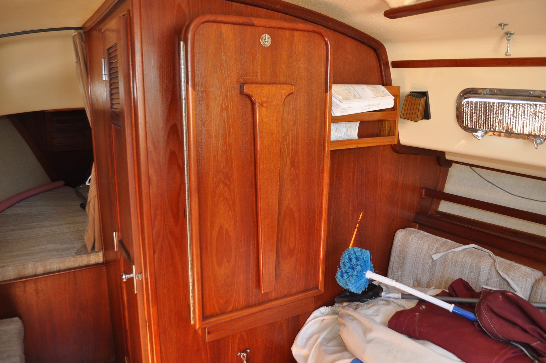 Interior of 1989 Island Packet 27 sailboat with wooden cabinetry and cozy sleeping area.