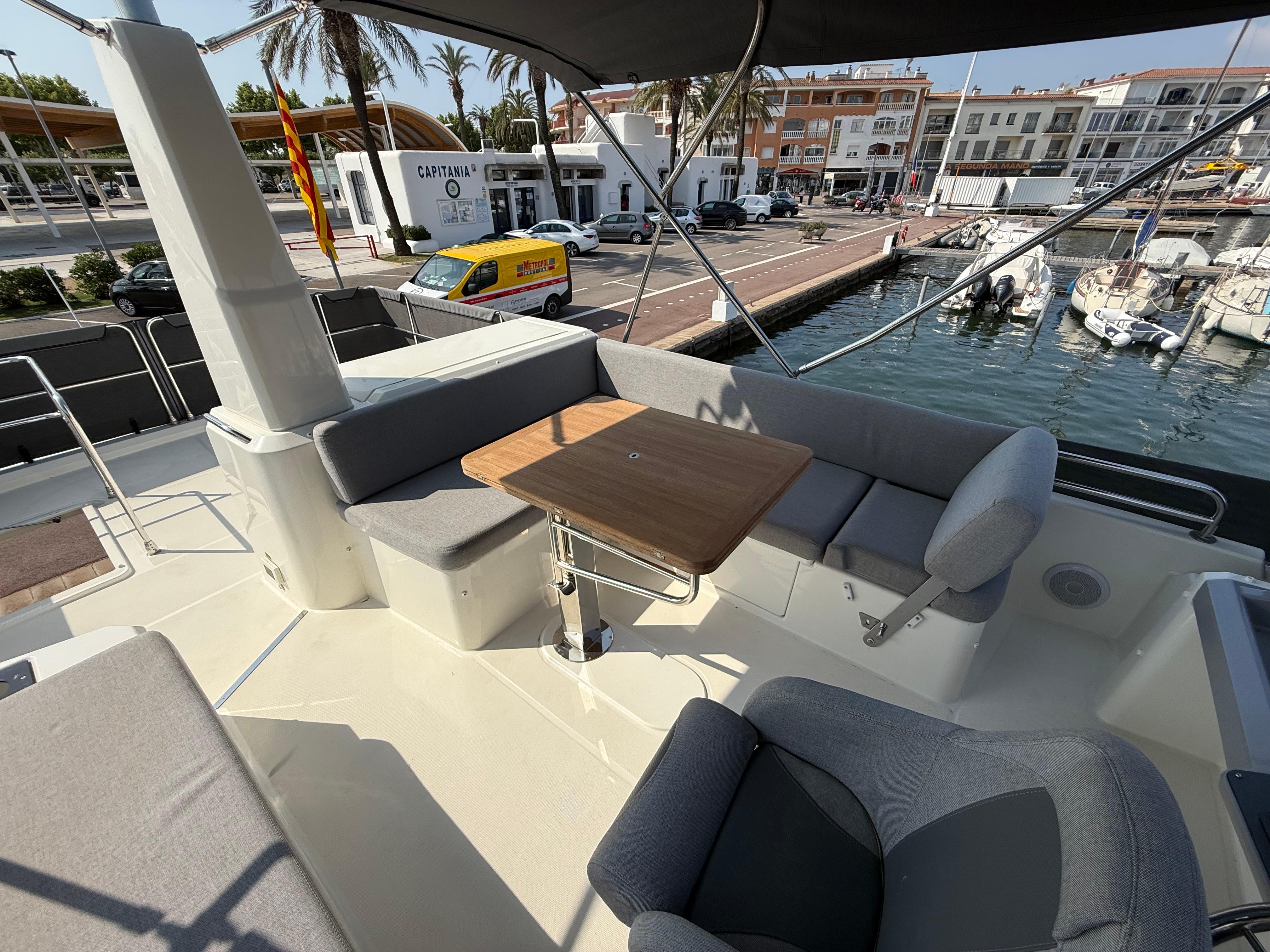 2023 Beneteau Swift Trawler 41 Fly deck with seating and table, docked at marina.