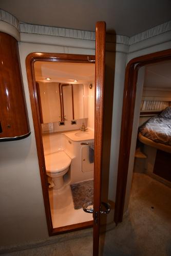 Interior of 2003 Sea Ray 460 Sundancer yacht, featuring a compact bathroom and cozy bedroom.