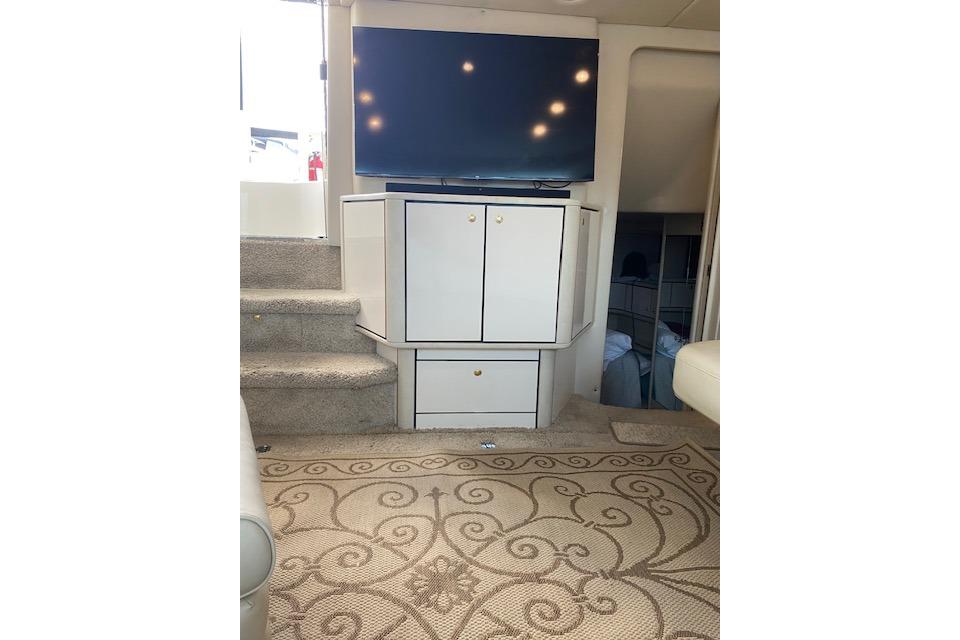 Interior of 1997 Sea Ray 370 Aft Cabin with TV, cabinets, and carpeted stairs.