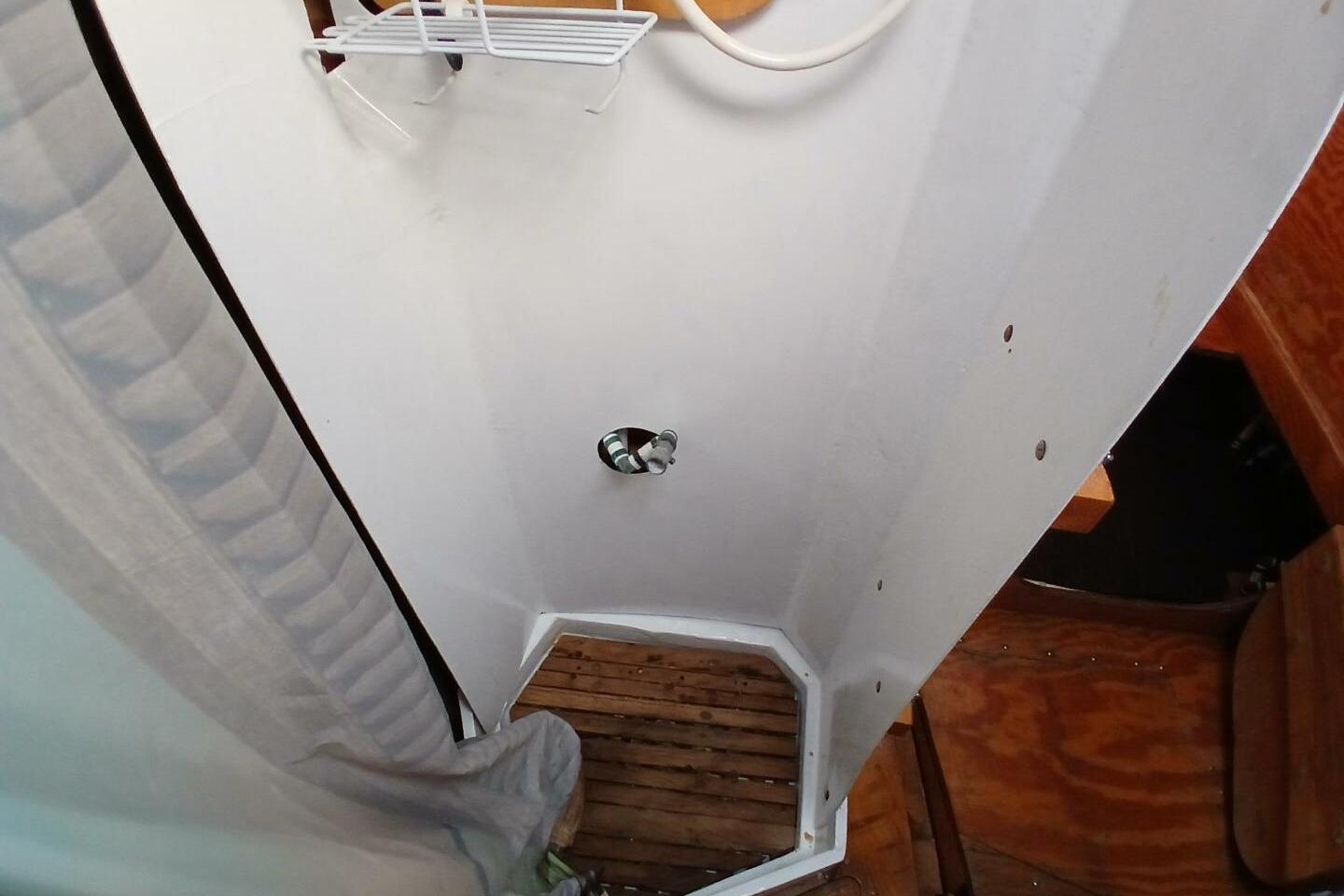 1976 Islander Freeport boat shower with wooden floor and white walls.