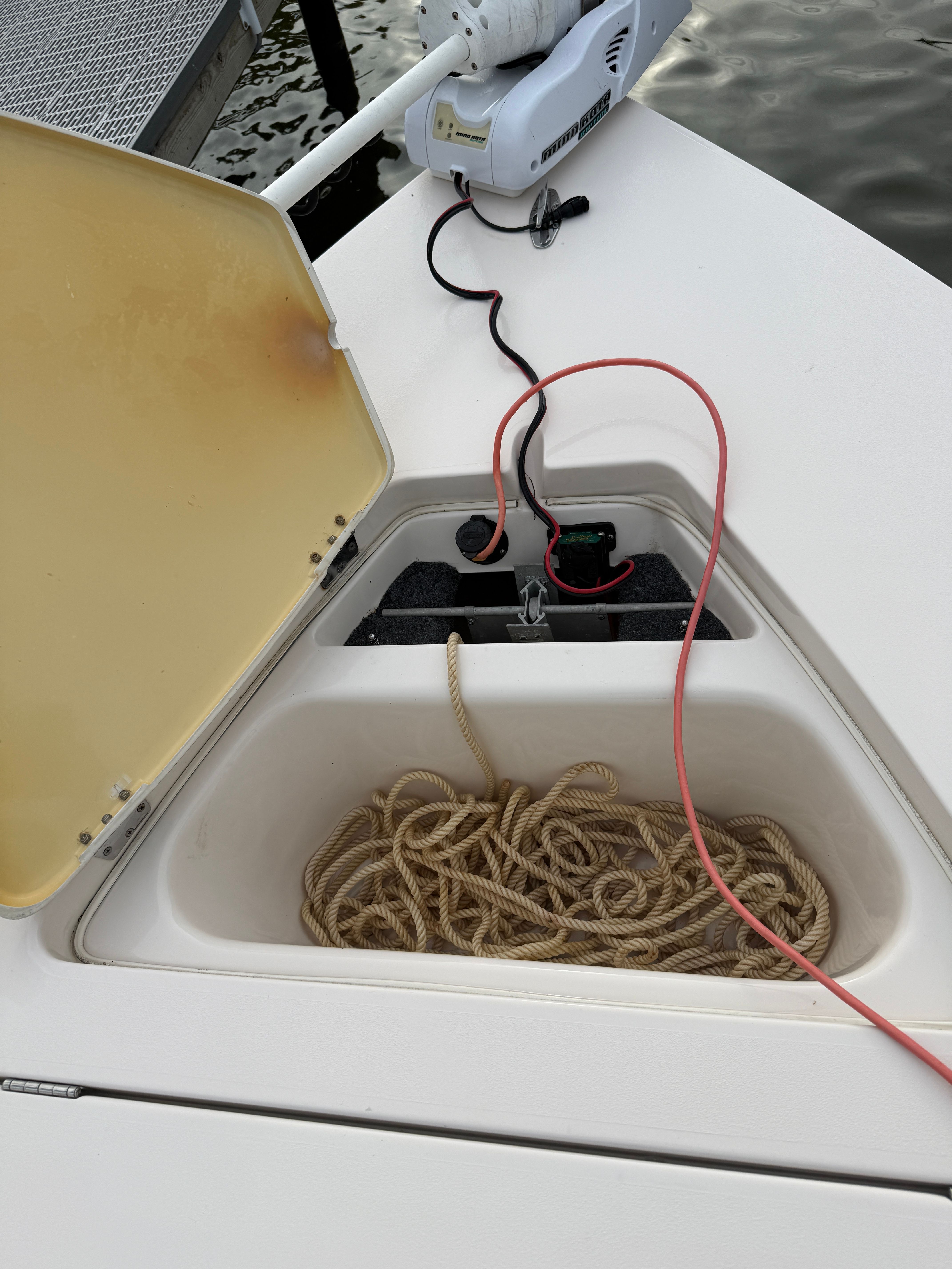 An open storage compartment on a boat with rope and cables.