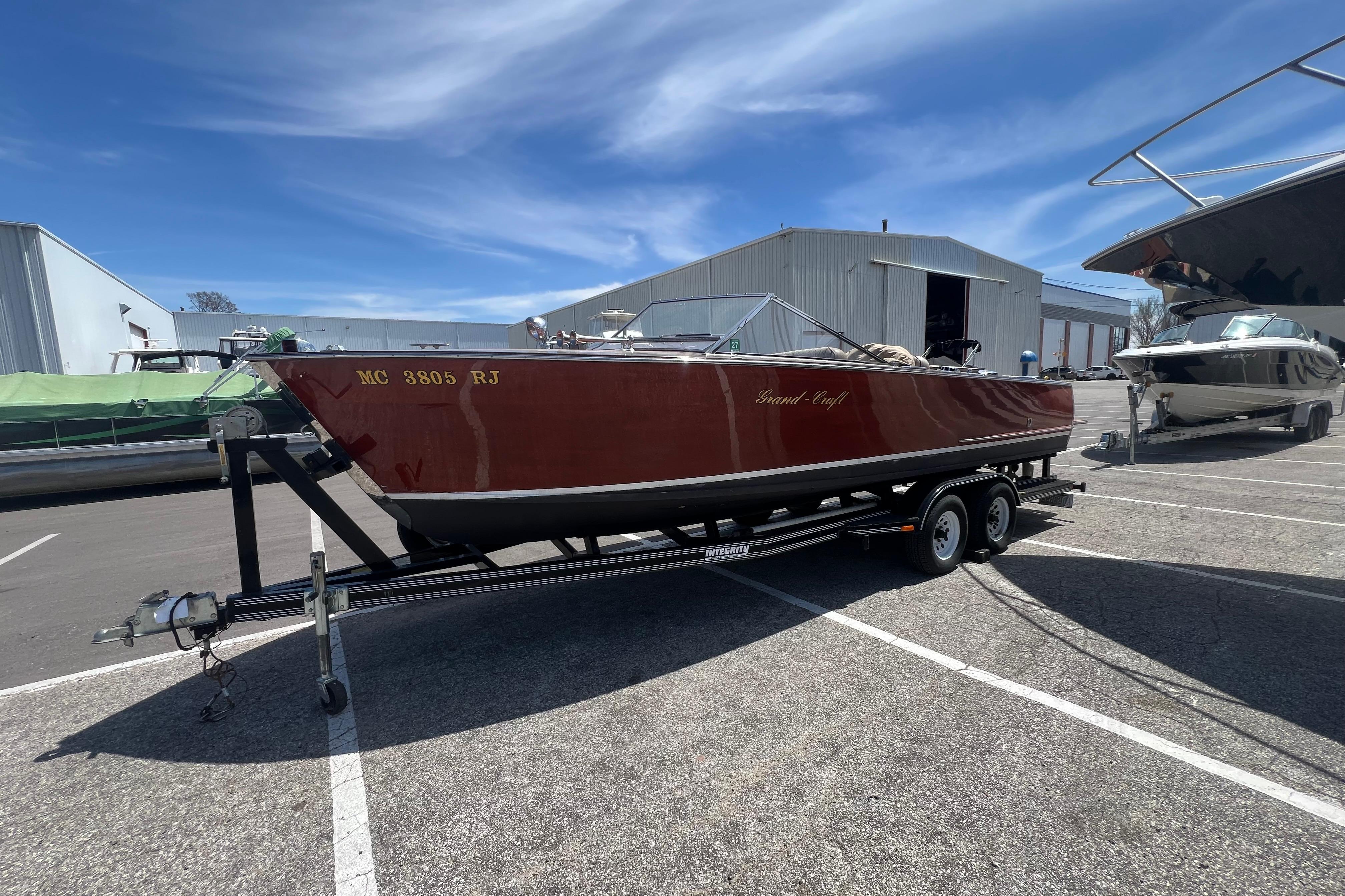 1997 Grand Craft 24 Luxury Sport boat on trailer in marina parking lot.