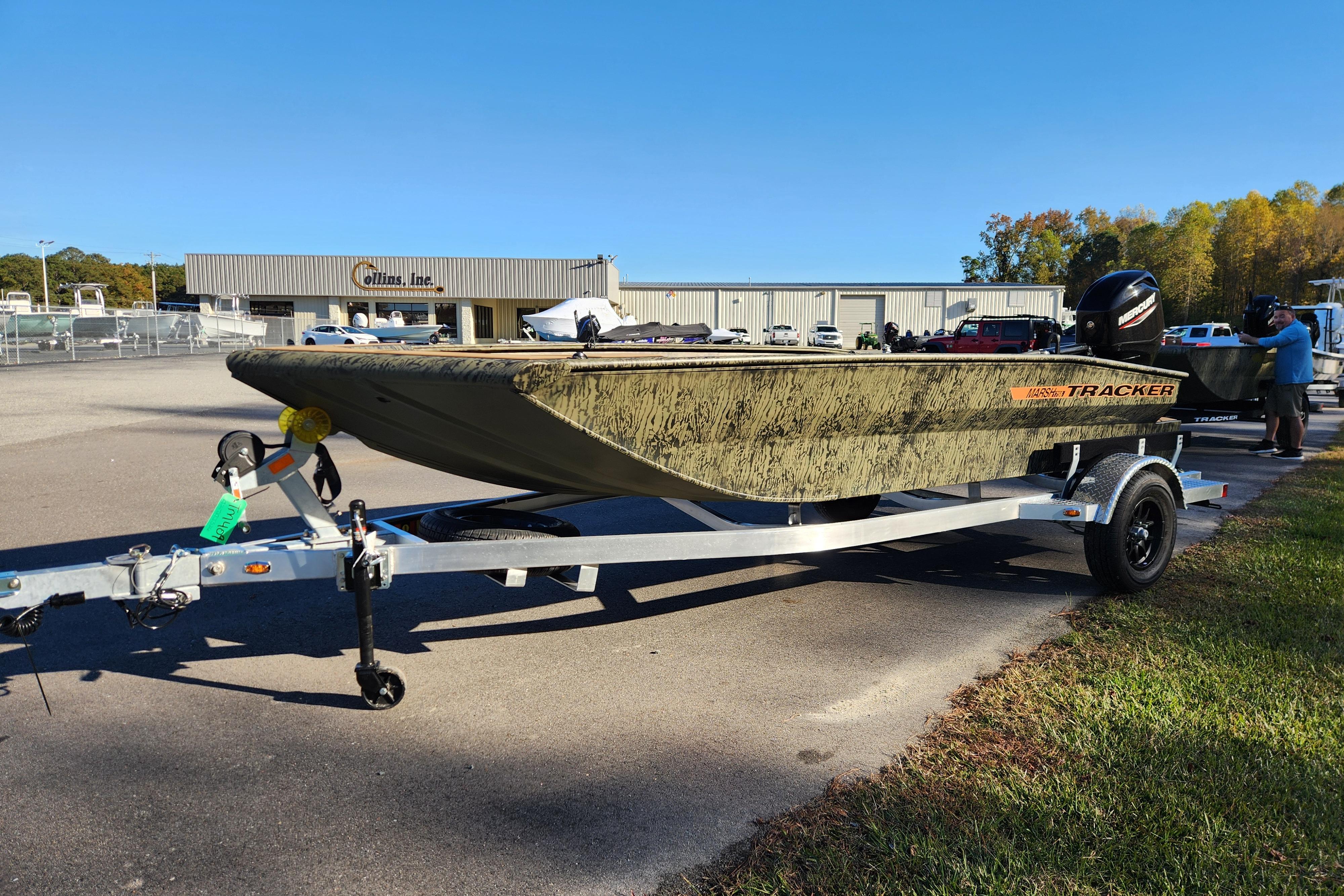 2026 Tracker Grizzly 1756 T Marsh boat on trailer, parked outdoors near Collins Inc. building.