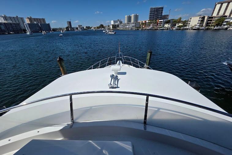 1993 McKinna 48 Pilothouse yacht on calm waters with city skyline in background.