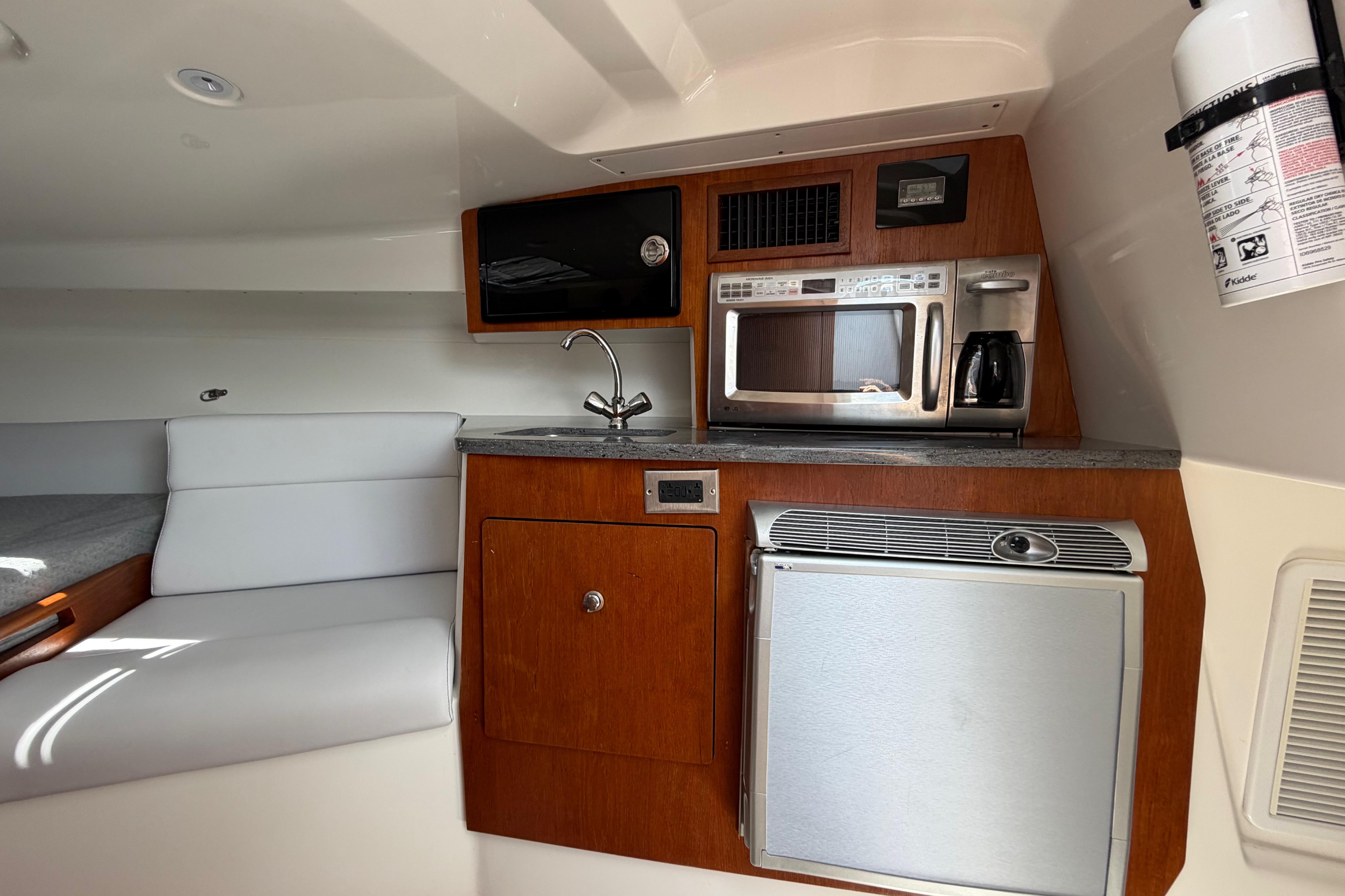 Compact kitchen area in a 2009 Everglades 350LX boat with modern appliances.