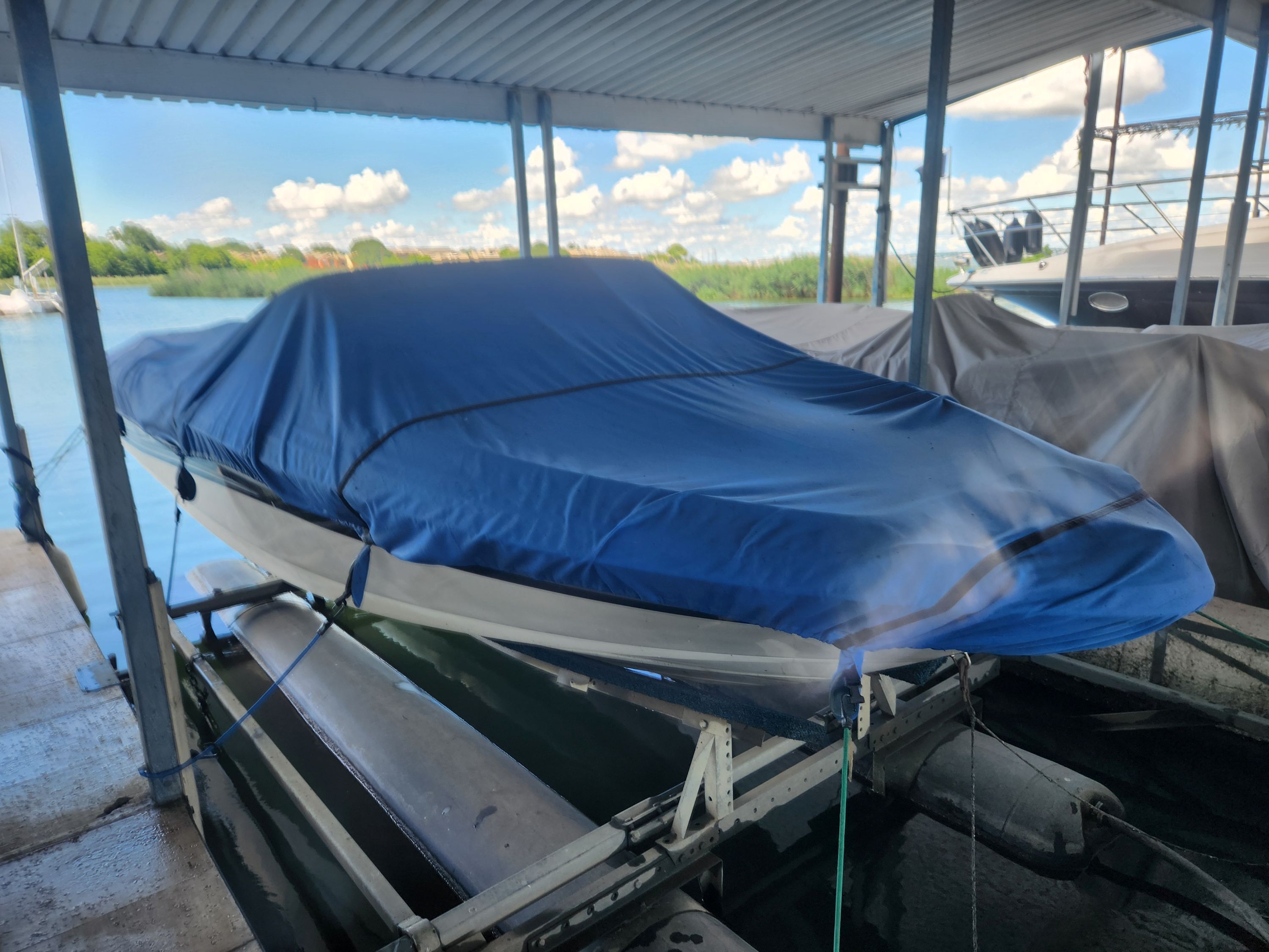 2004 Sea Ray 185 boat with blue cover in dock.