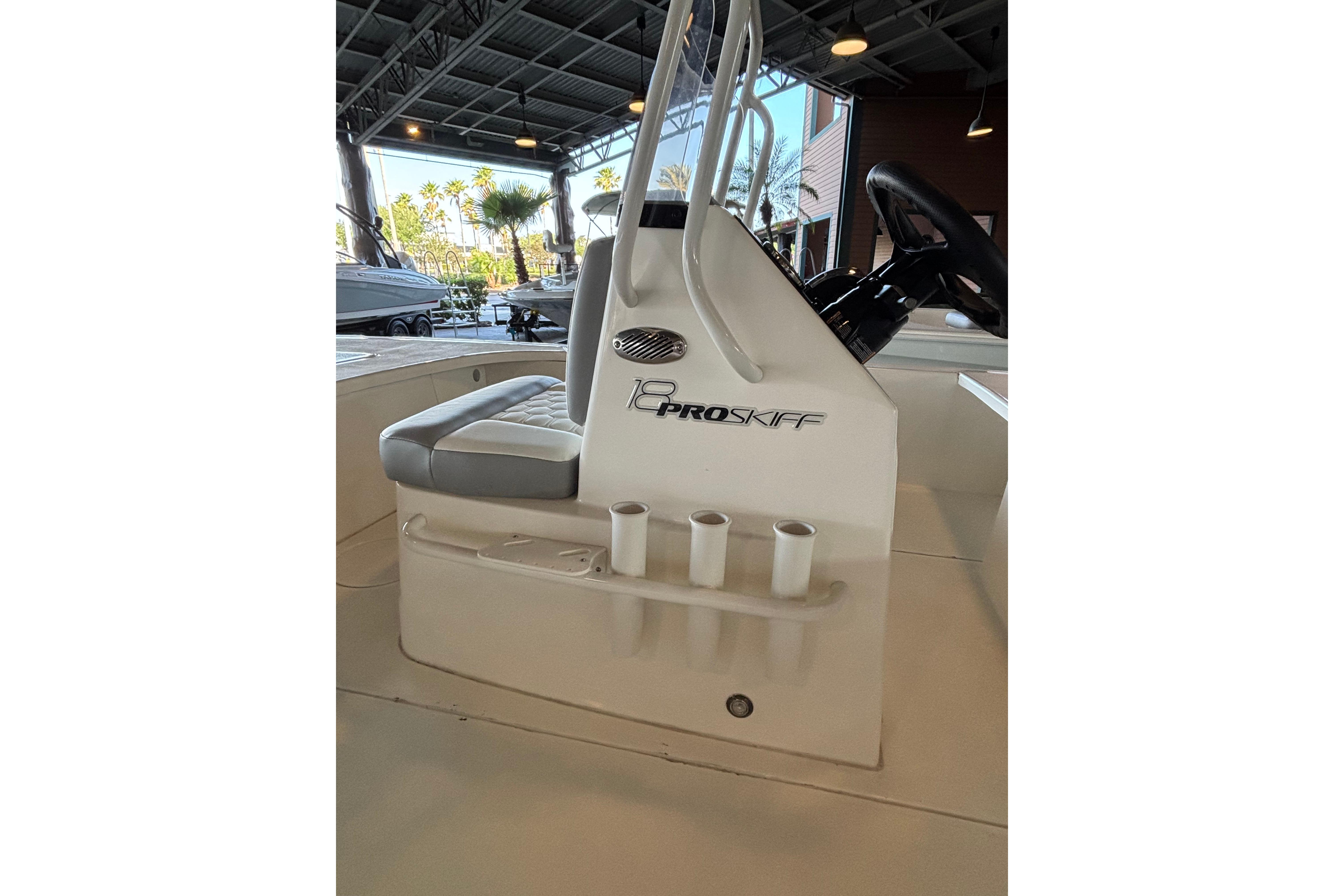 2026 Mako 18 Pro Skiff boat interior with seating and steering wheel in a showroom.
