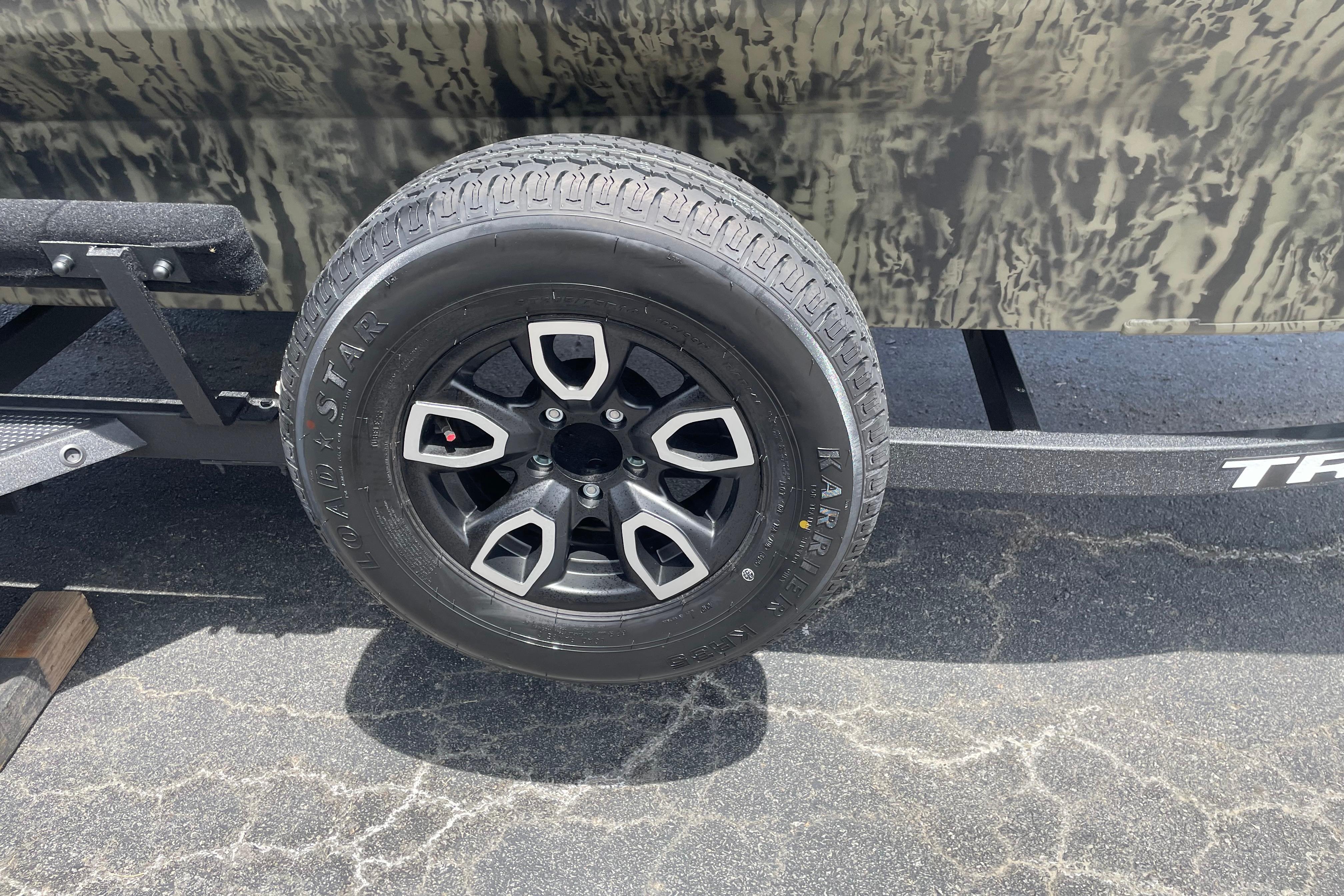 Trailer wheel of 2026 Tracker Grizzly 1756 T Marsh boat on pavement.
