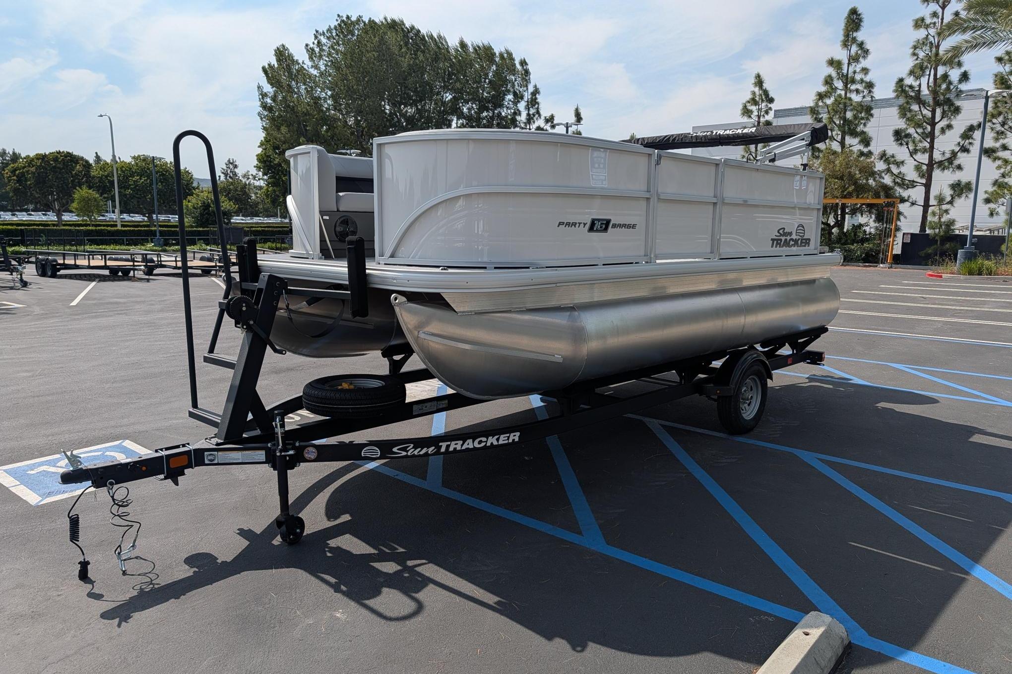 2026 Sun Tracker Party Barge 16 DLX pontoon boat on trailer in parking lot.