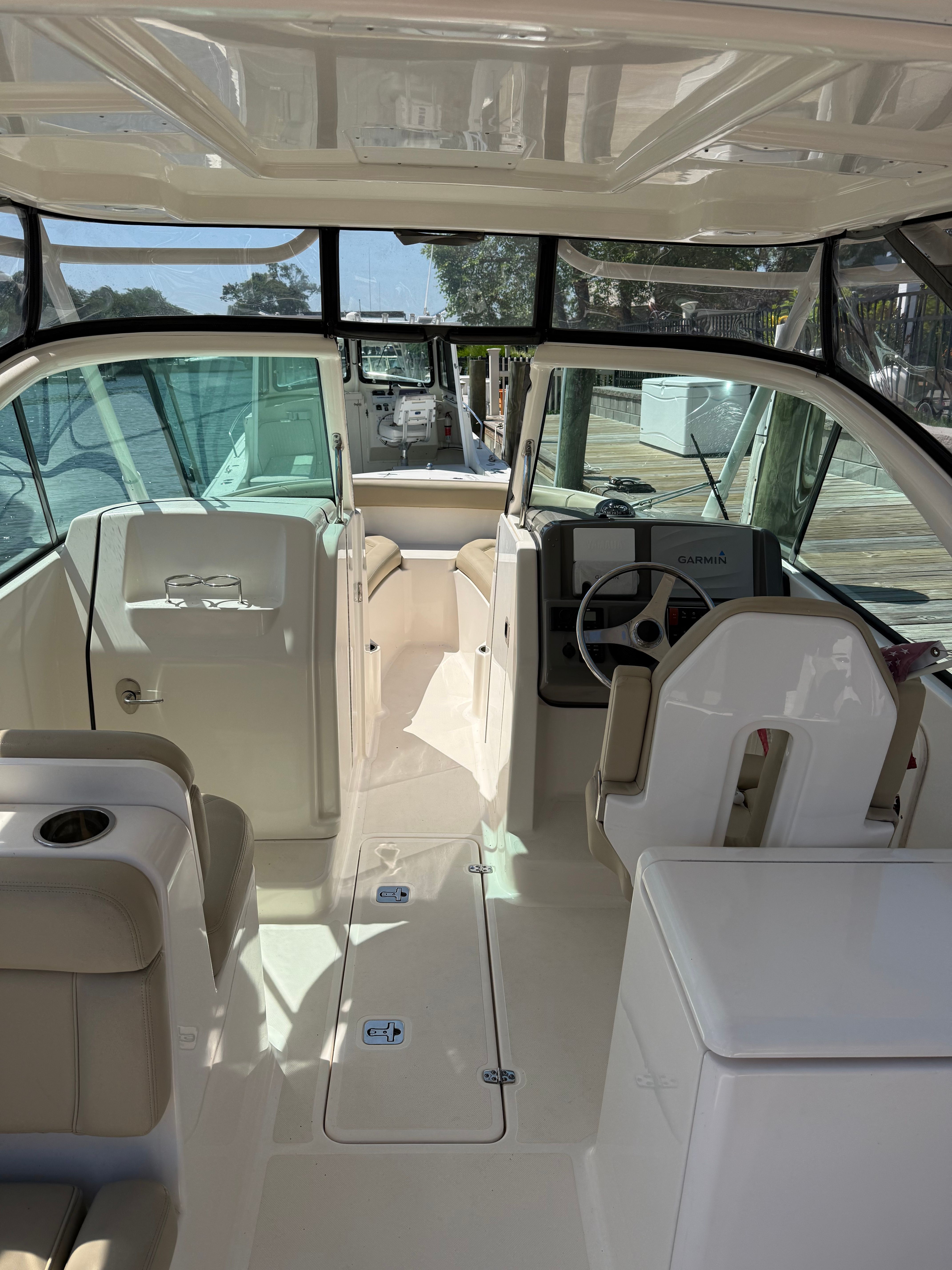 Interior view of a Pursuit DC 265 Dual Console boat with beige seating and a helm station.