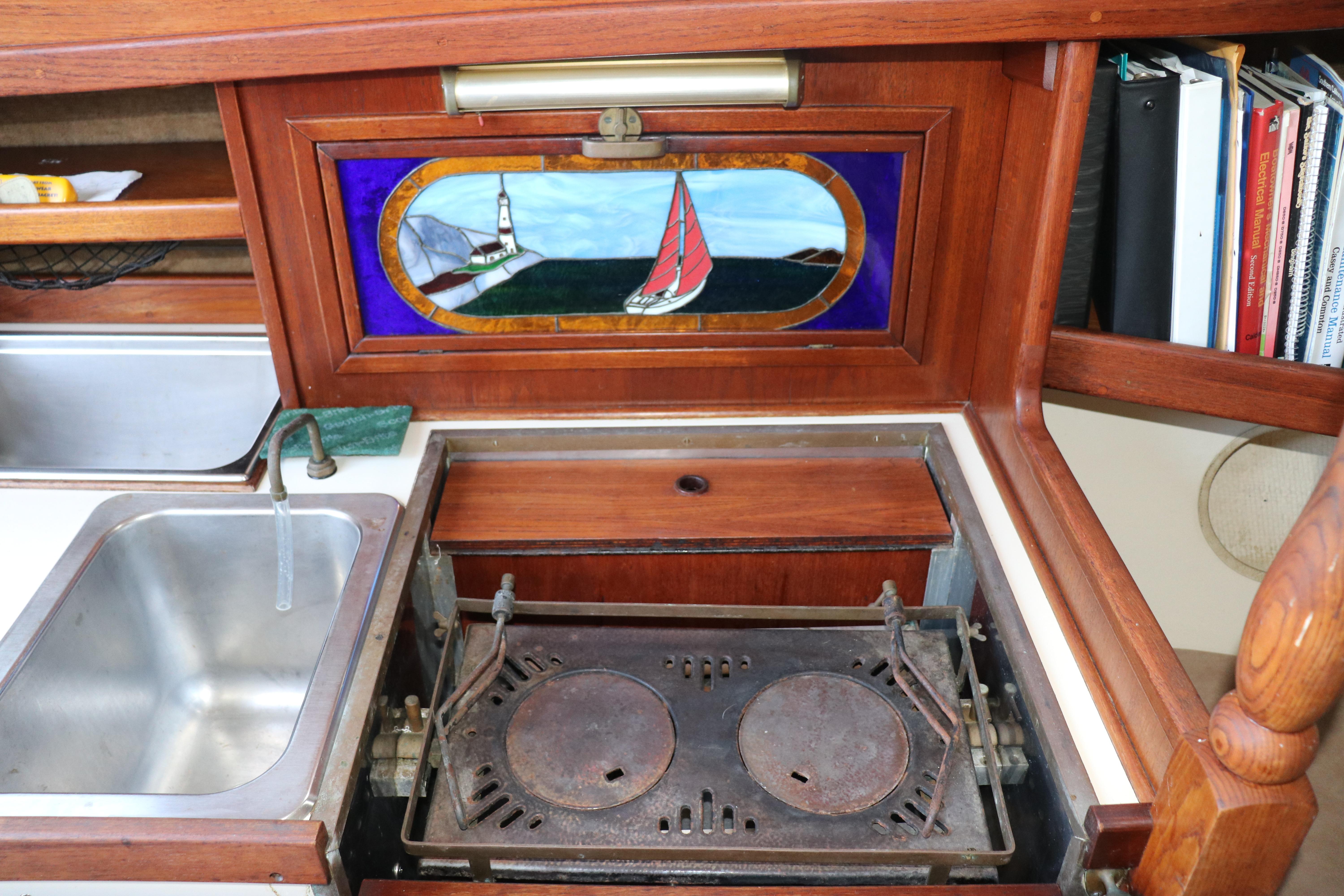 1982 Pacific Seacraft Flicka 20 interior with stove, sink, and nautical stained glass.
