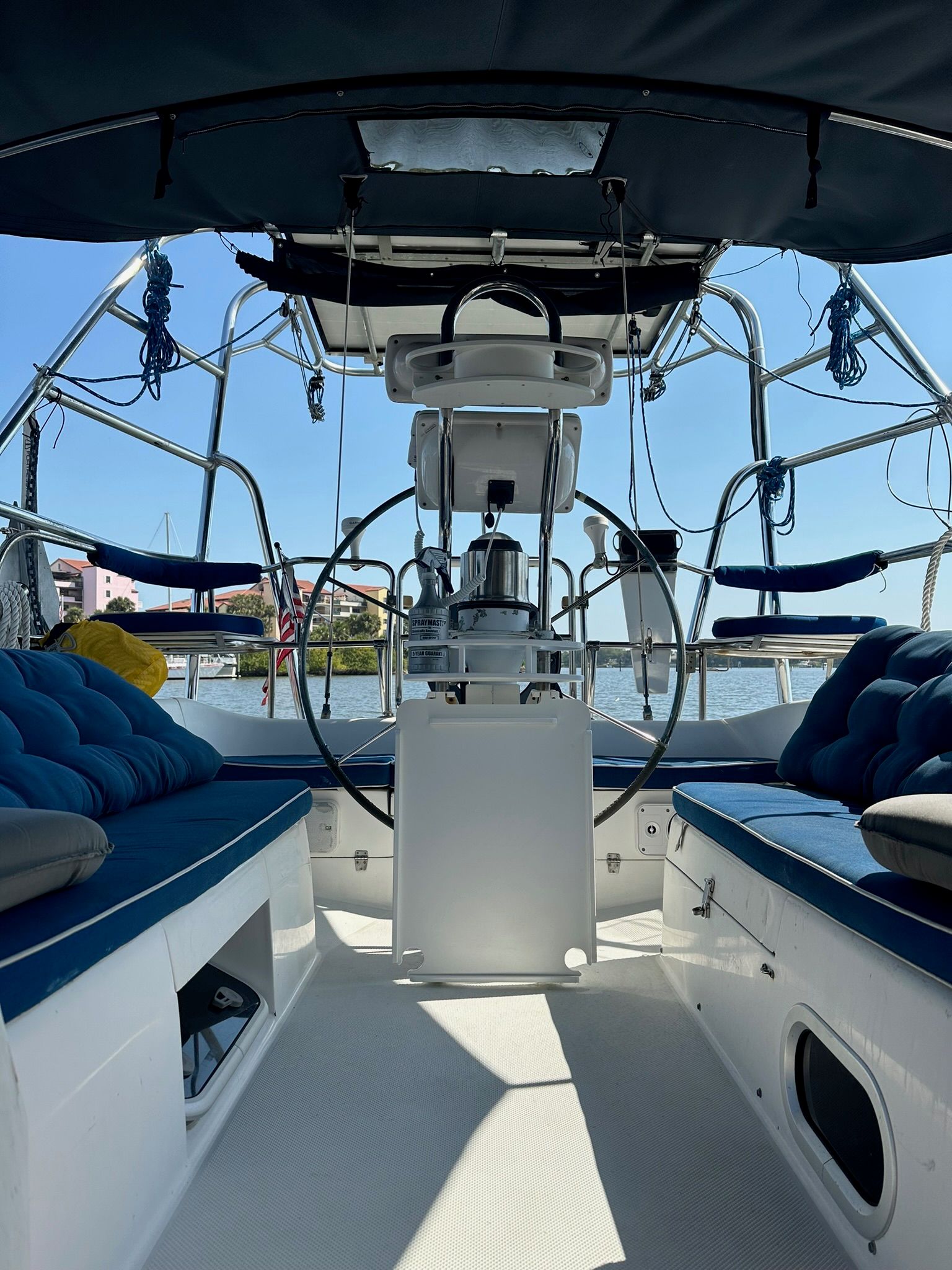 The cockpit of a Catalina MkII yacht with blue cushions and a steering wheel.