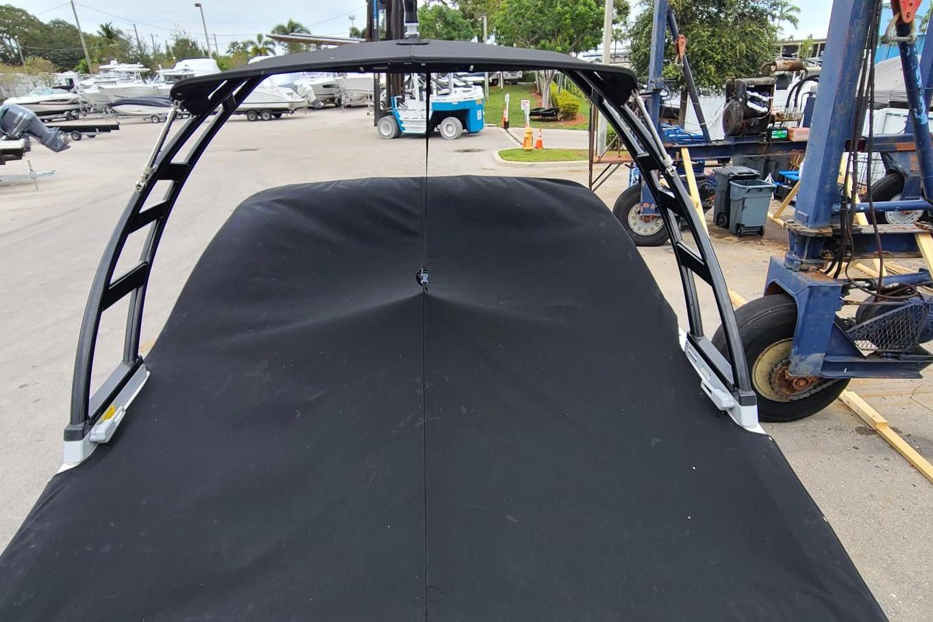 2020 Chaparral 21 SSi OB boat with black cover in a marina setting.