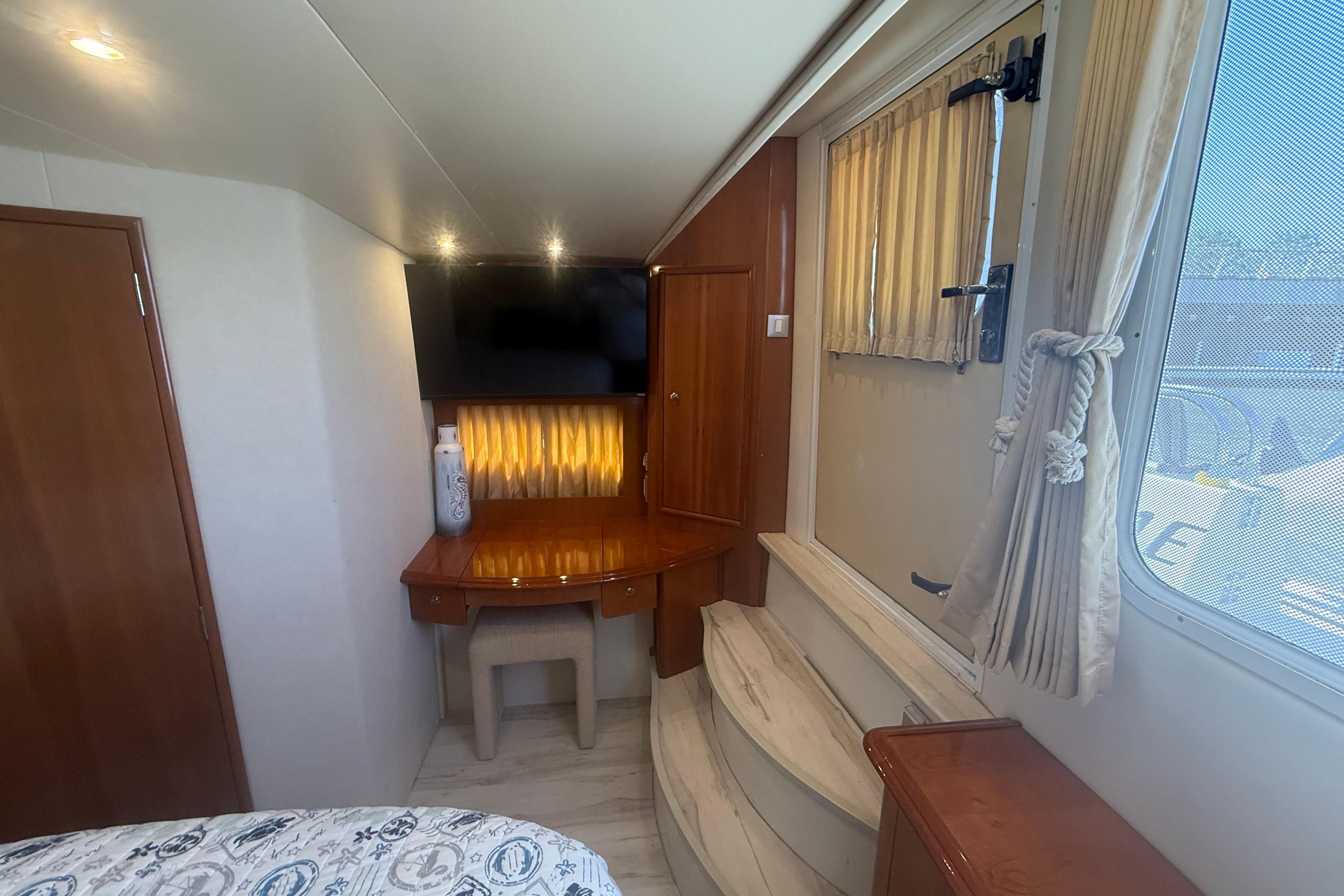 Interior of 2006 Carver 43 Motor Yacht with TV, desk, and window with curtains.