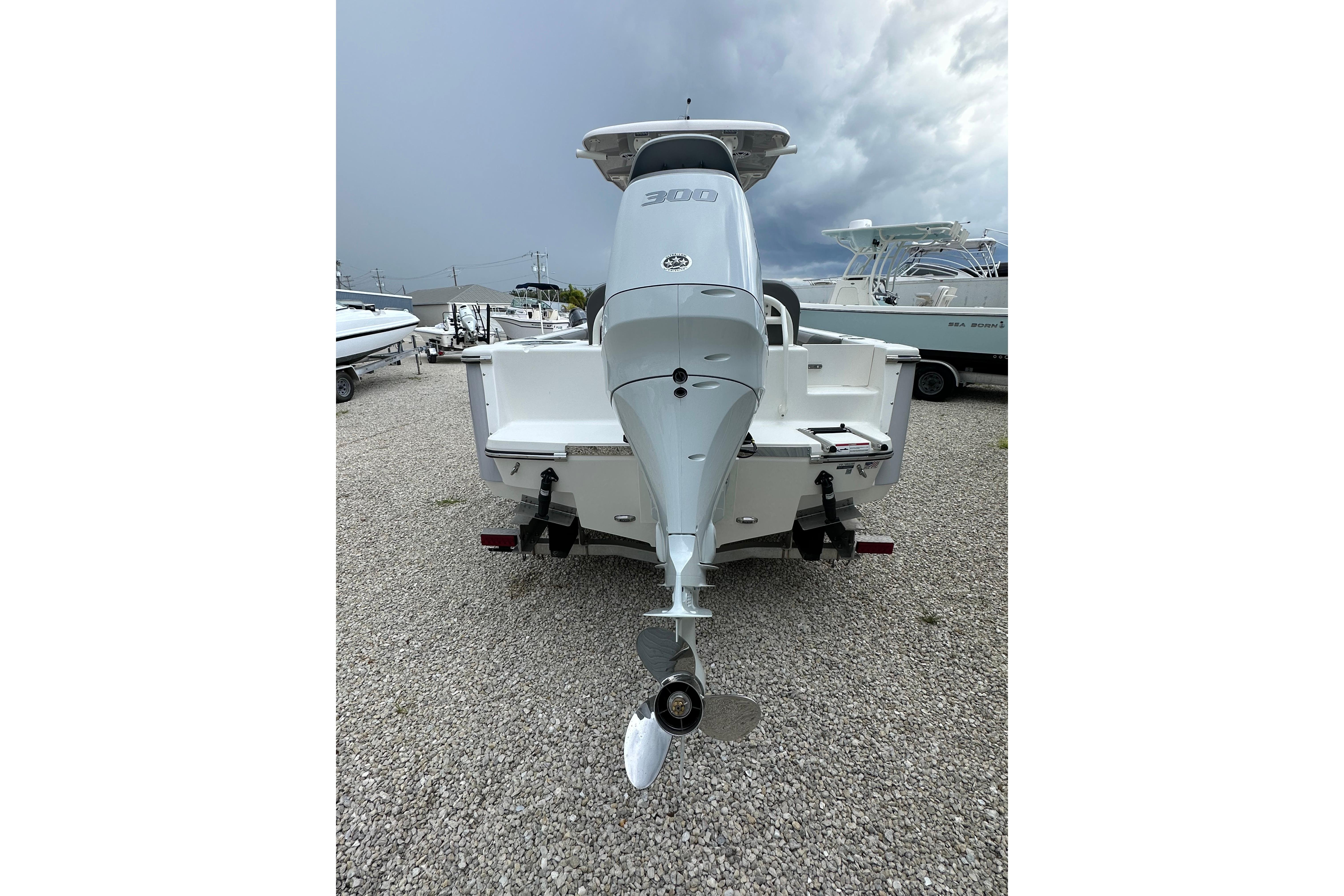 2027 Sea Born LX24 Center Console boat with powerful outboard motor, parked on gravel.
