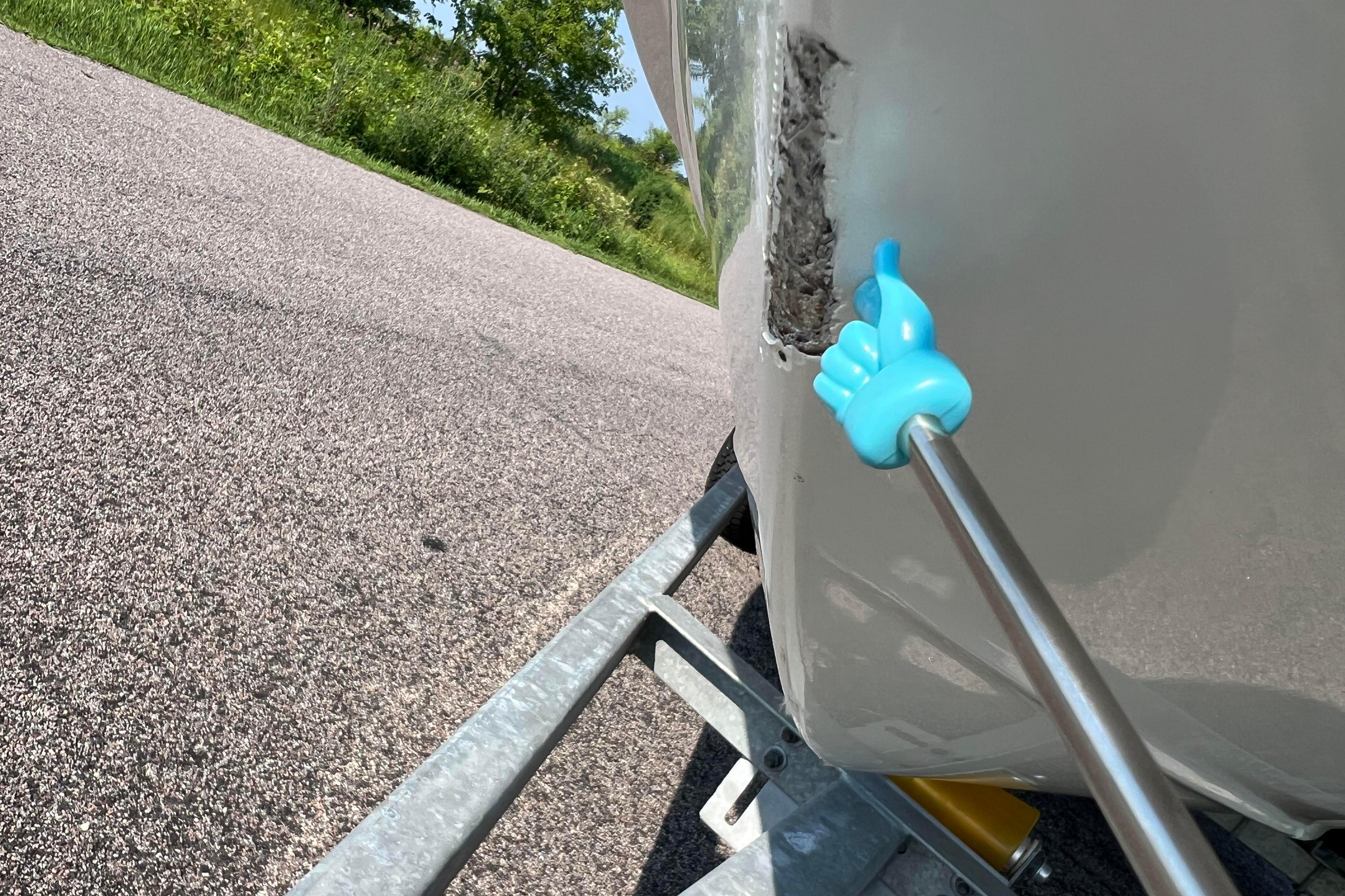 Damaged 2012 Sea Fox 206 Center Console boat hull on trailer, with tool pointing at crack.