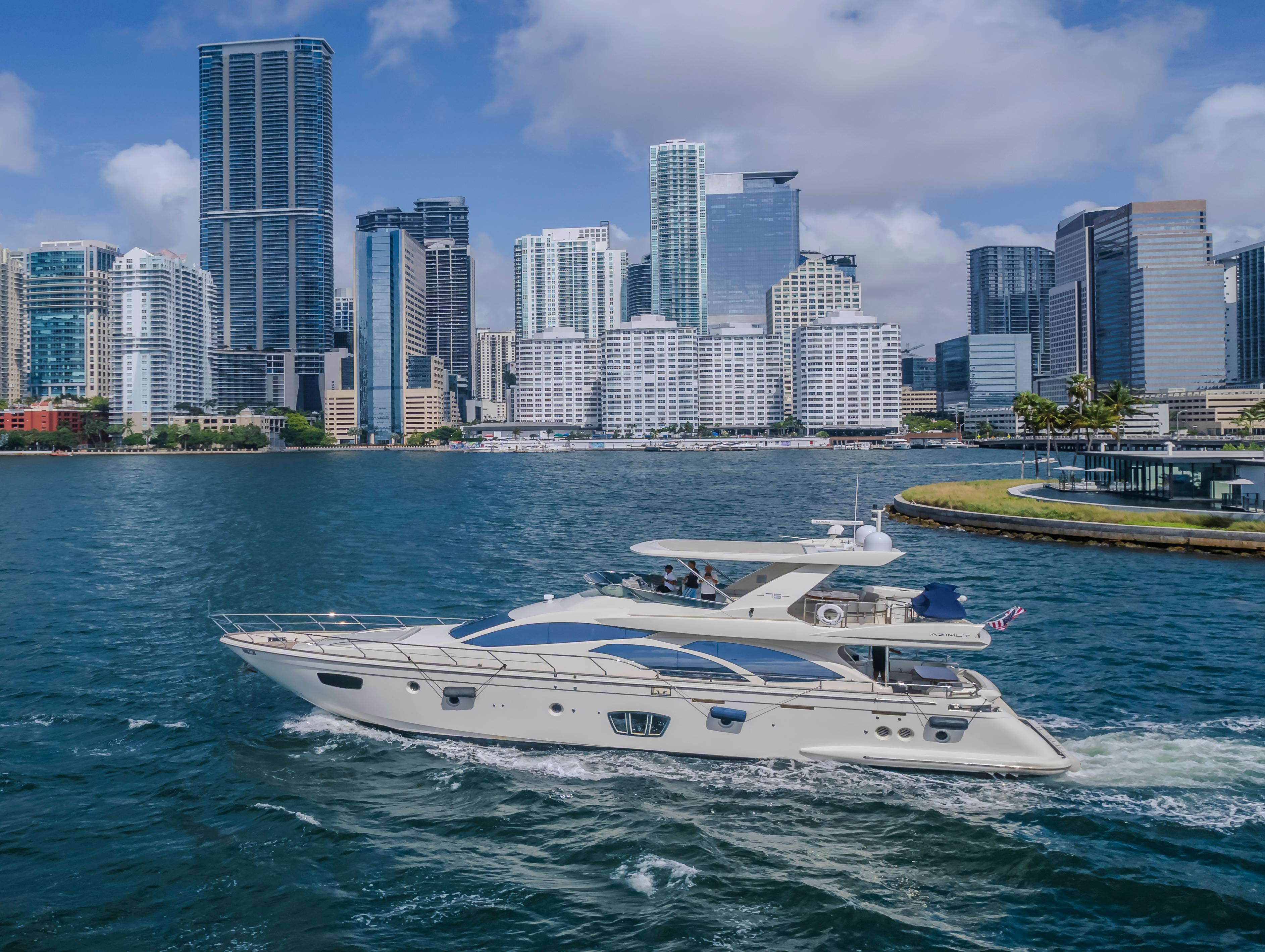 Azimut Flybridge 2008 yacht cruising near a city skyline with skyscrapers and blue sky.
