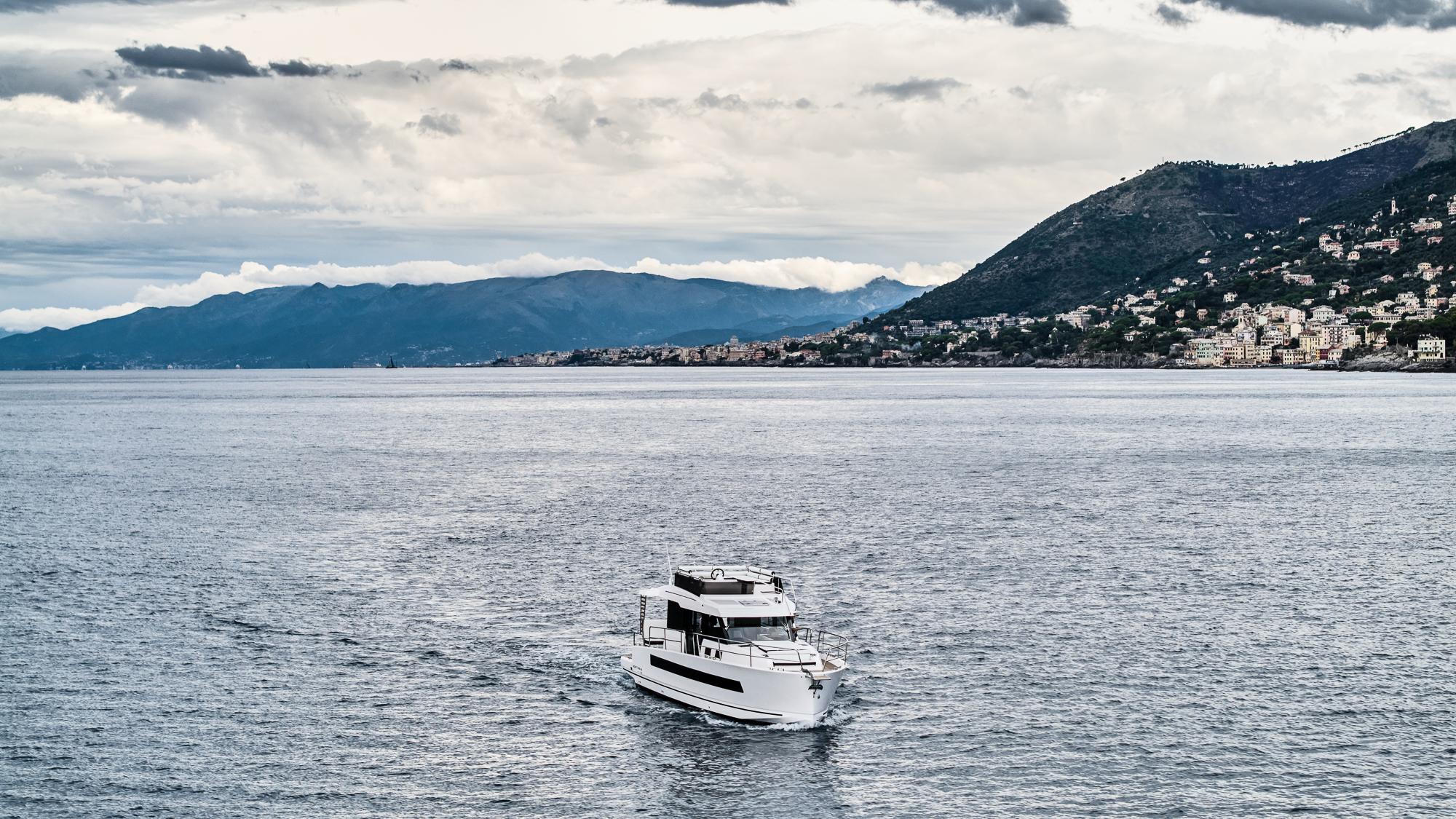 2025 Northman 1300 yacht cruising on a scenic coastal waterway with mountainous backdrop.