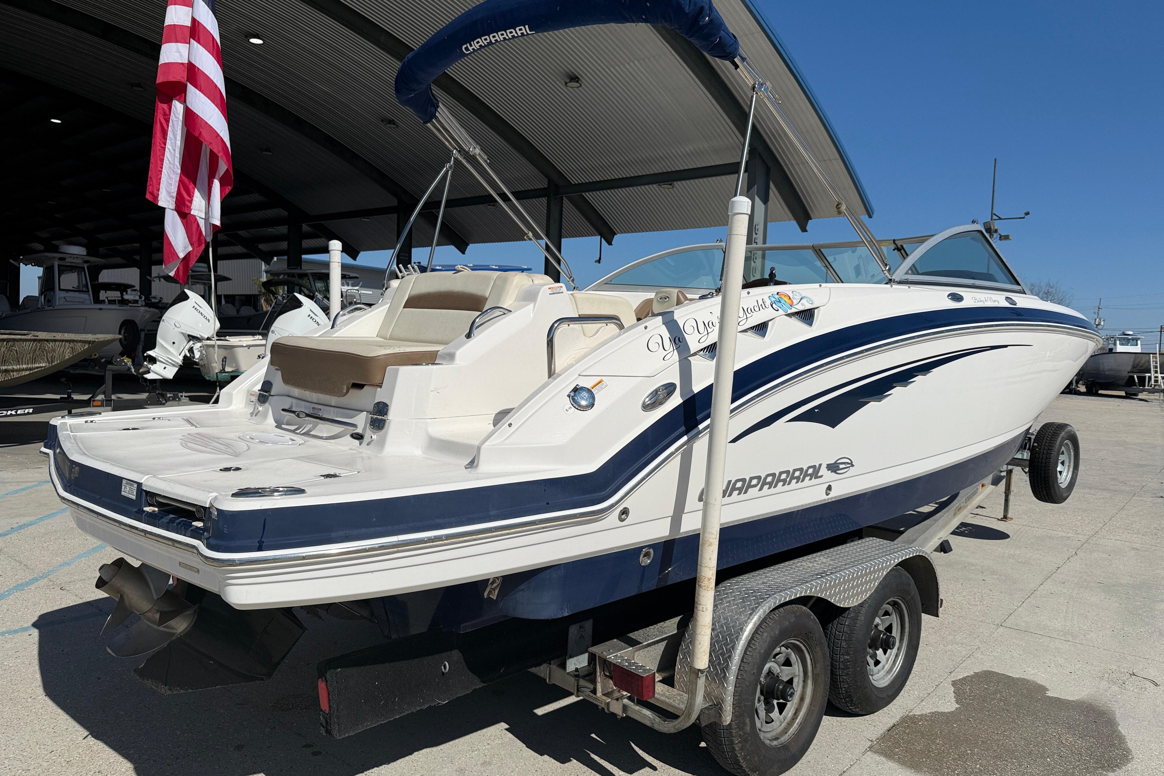 2014 Chaparral 264 Sunesta boat on trailer, displayed outdoors with American flag.