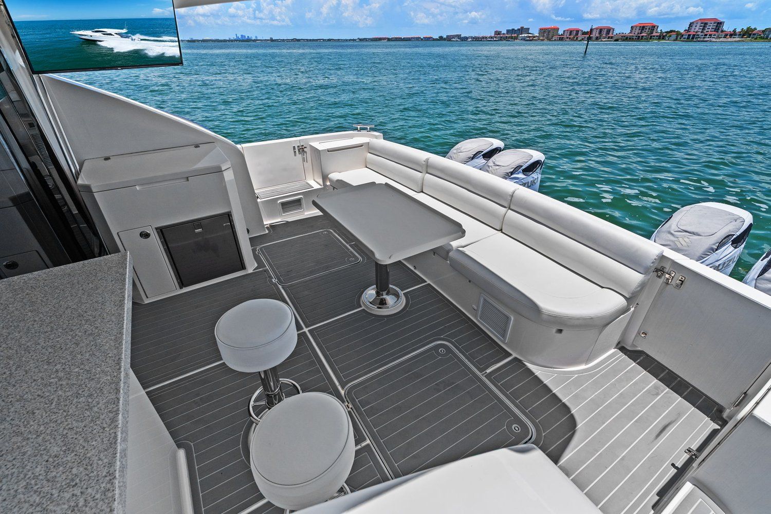The image shows the deck of a 2018 Mym/Mares 47 Outboard Express Catamaran with seating and a table.