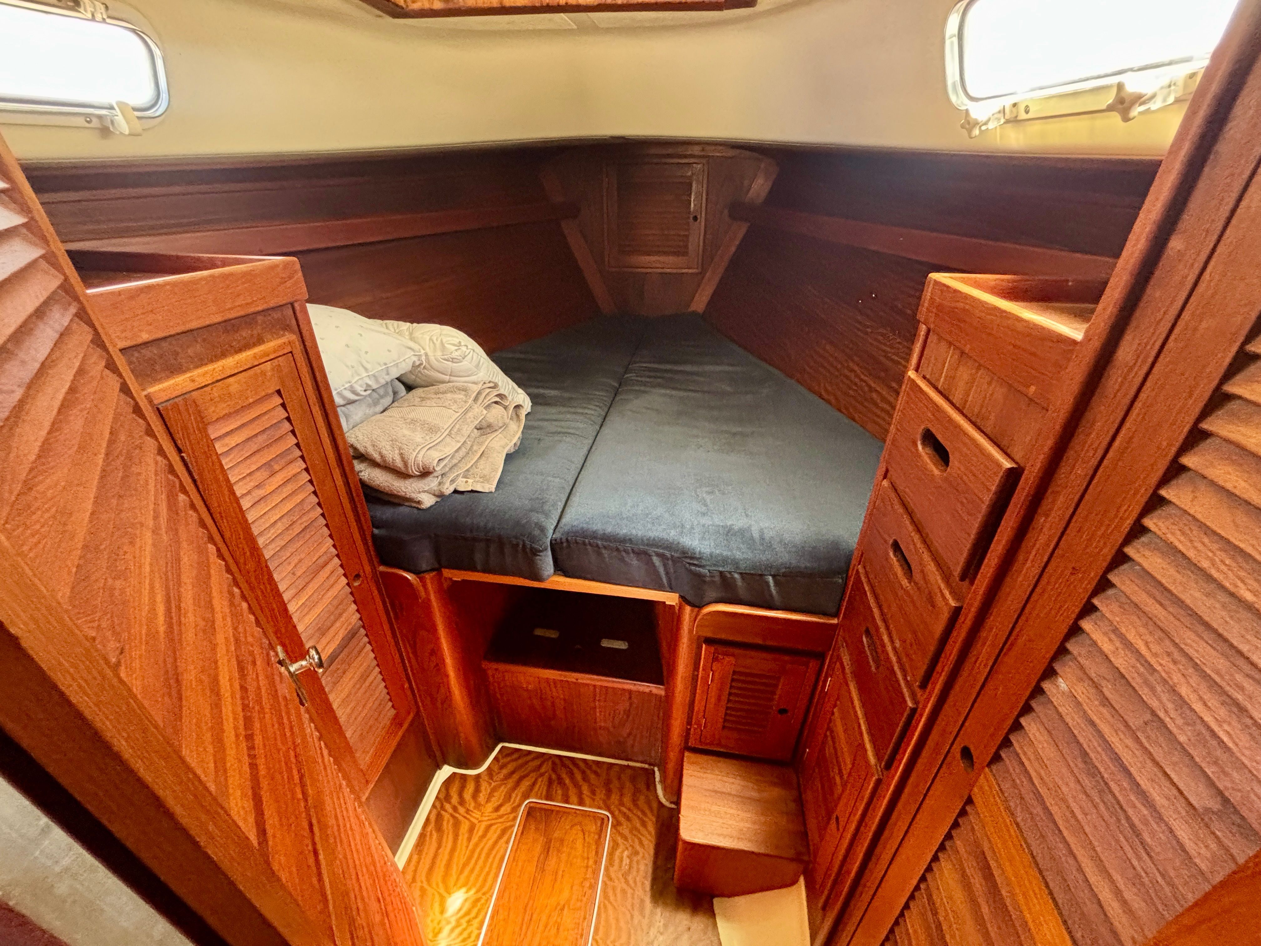 The cabin of a 1979 Tartan 37 with wood paneling and a V-shaped bed.