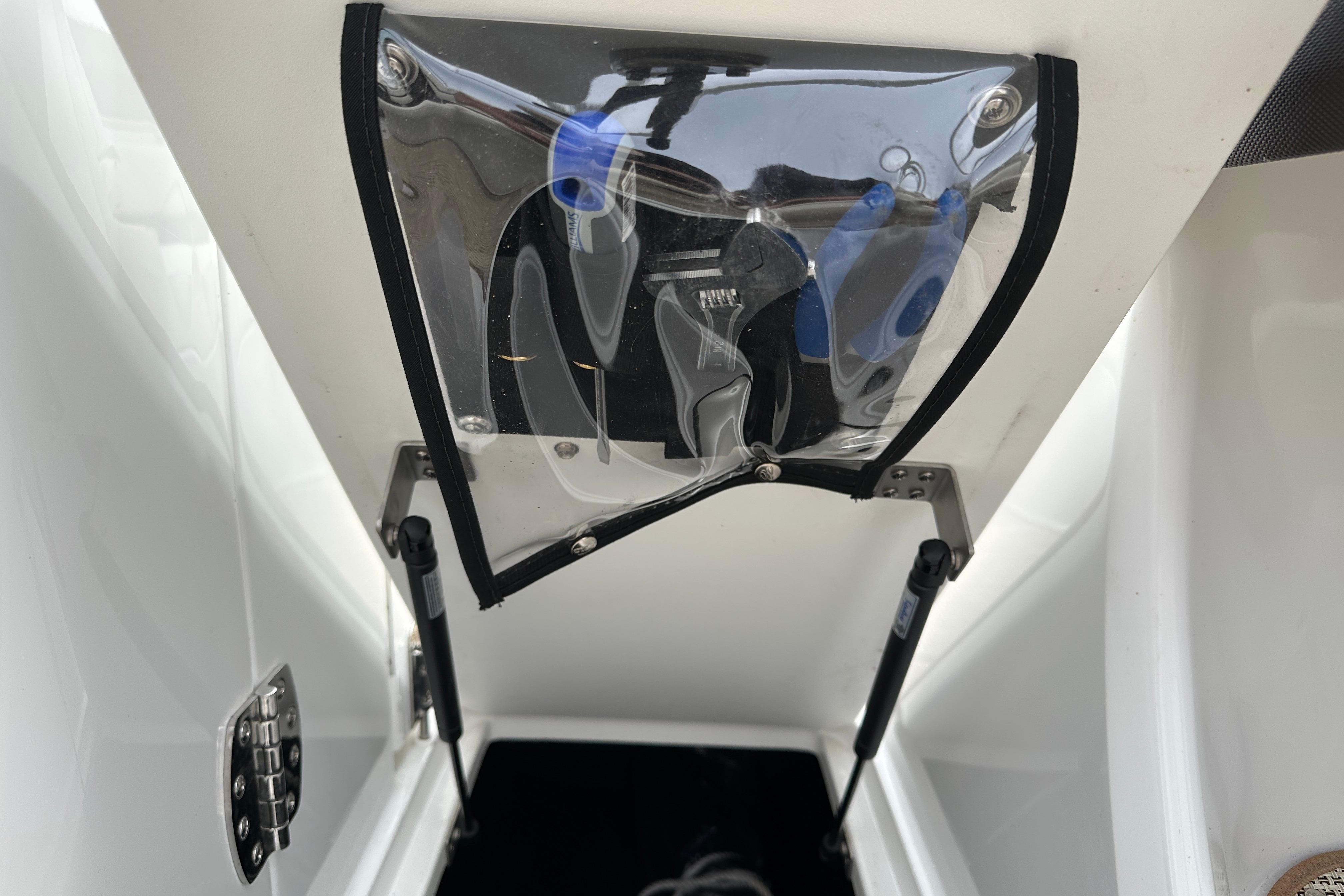 Storage compartment of a 2019 Cobalt R5 boat with visible tools and hydraulic hinges.