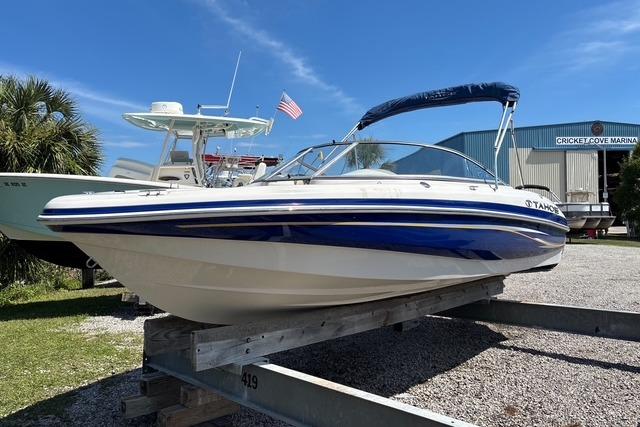 2012 Tahoe Q8 SSi boat on trailer at marina, blue and white design, sunny day.