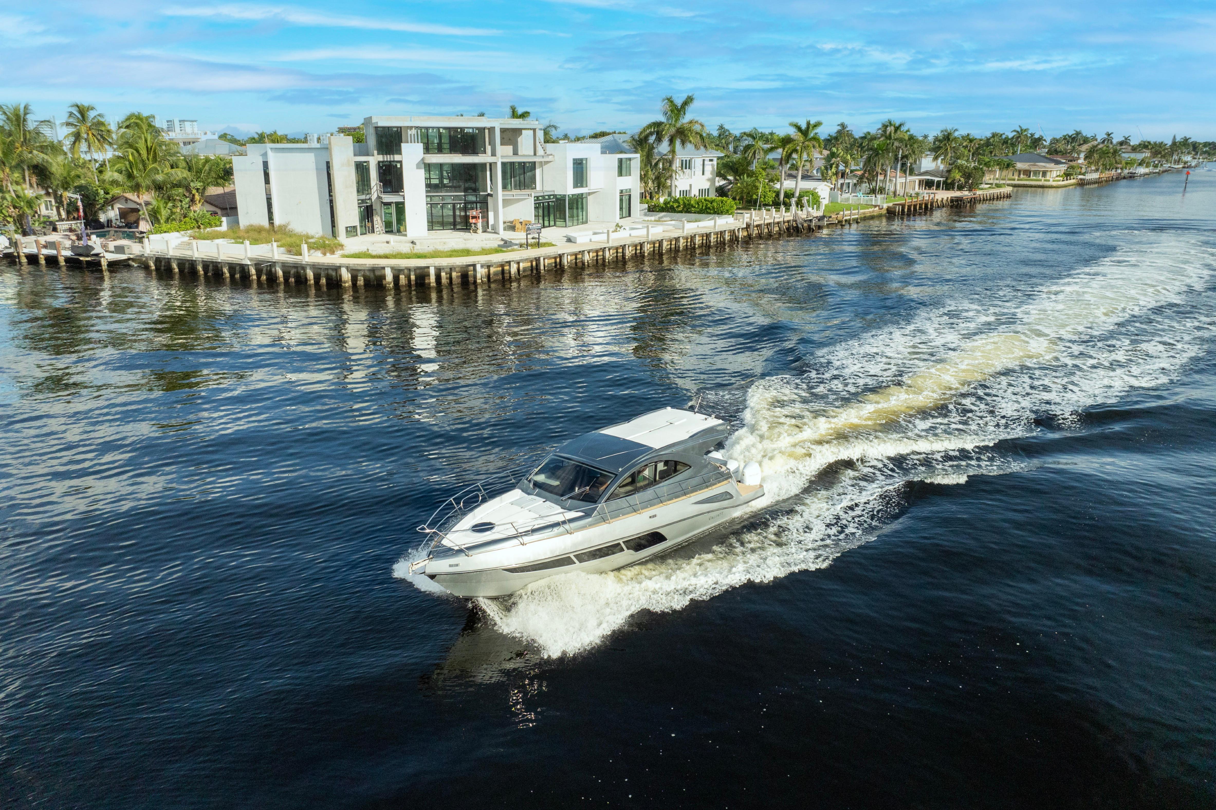 2025 Valiatt 410HT yacht cruising near modern waterfront homes.