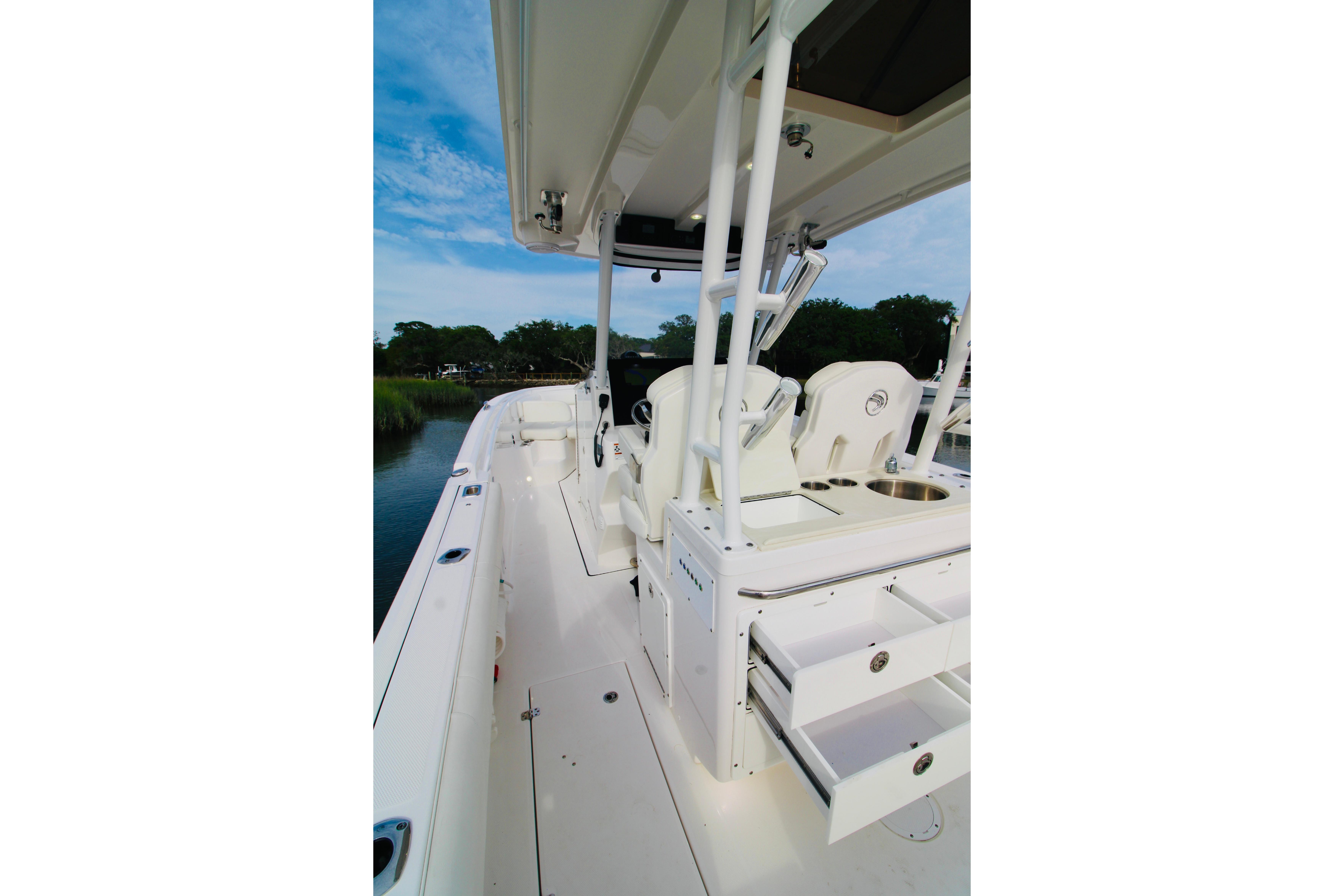 2022 Edgewater 280CC boat interior with seating and storage, docked by a scenic waterway.