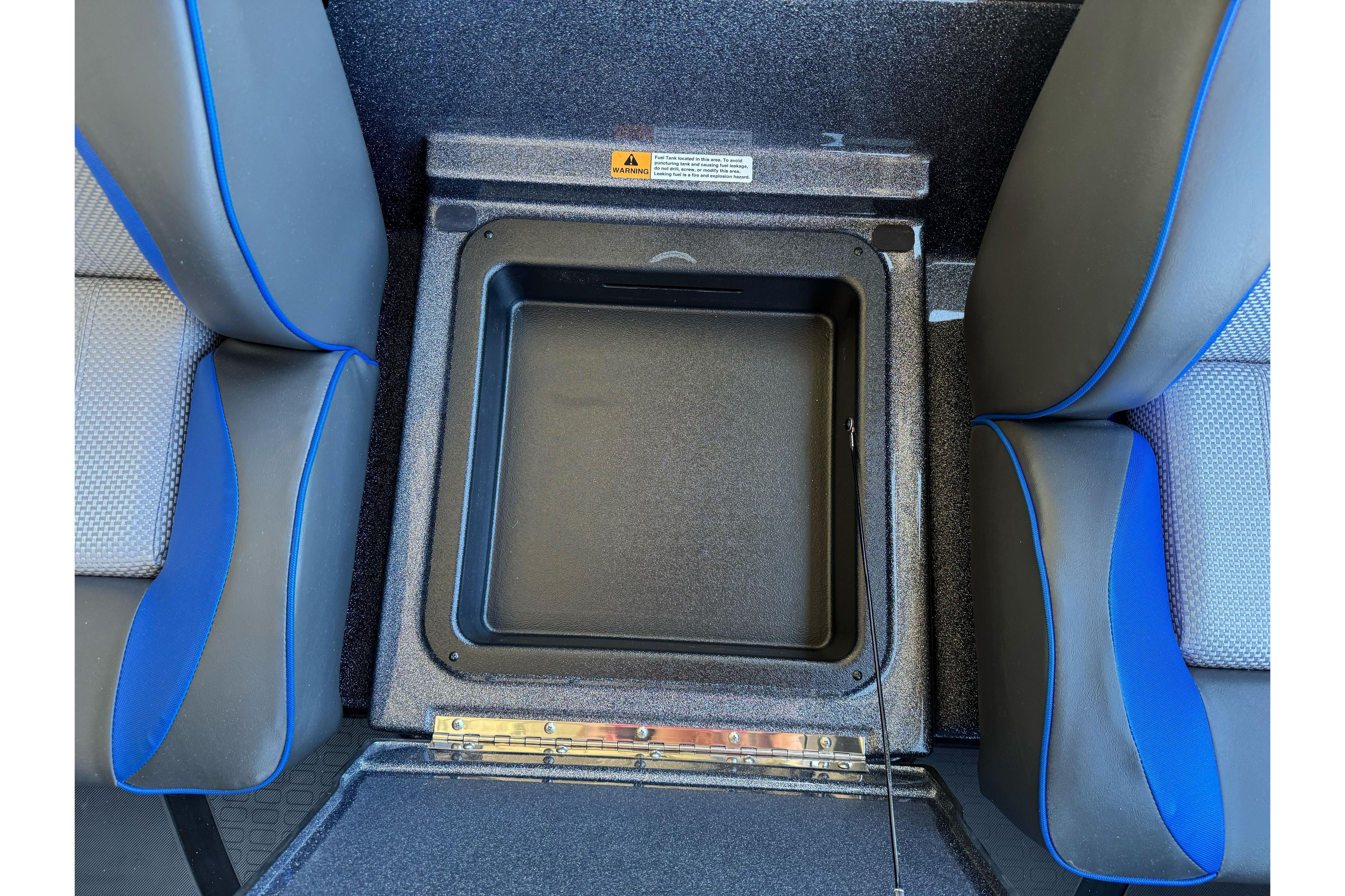 2026 Triton 21XP Patriot boat interior with storage compartment between blue-accented seats.