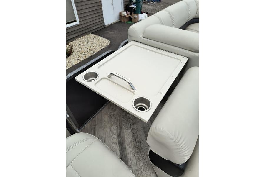 2017 Manitou 25 Oasis SE boat interior with table and cup holders.