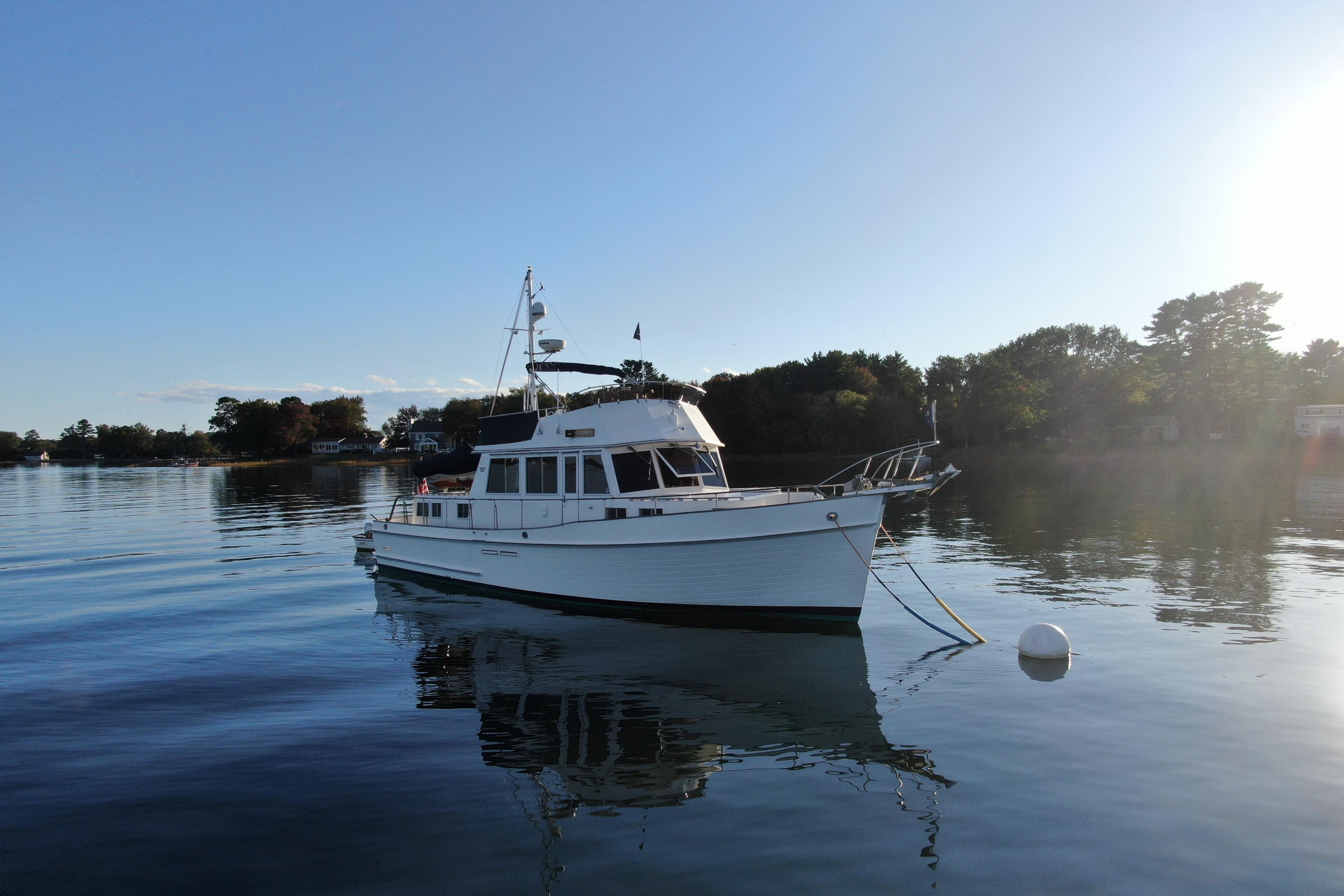 1989 Grand Banks 46 Classic yacht on calm water, surrounded by trees.