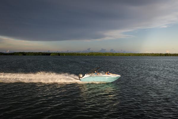 2025 Hurricane SunDeck 235 OB speeding on open water under cloudy sky.
