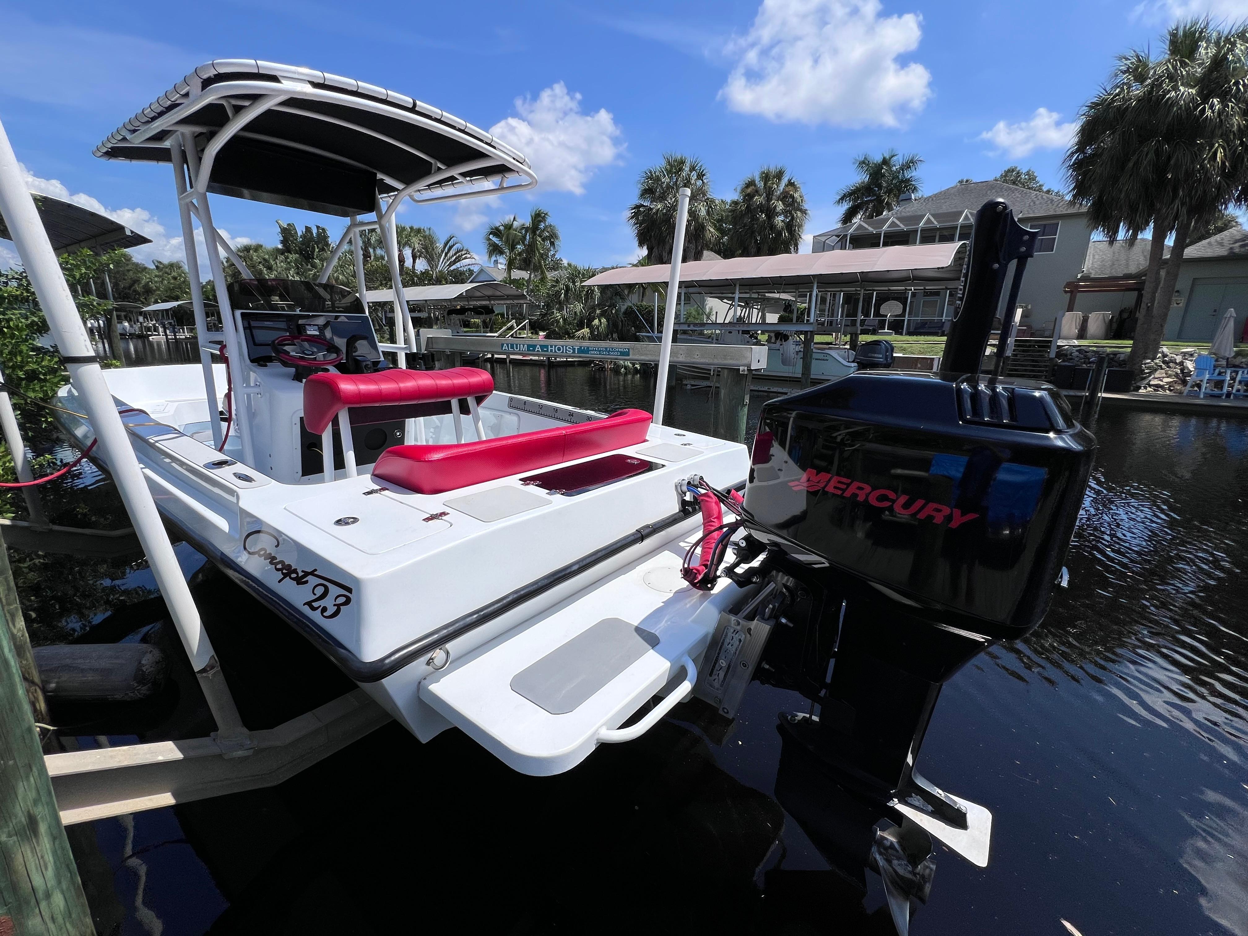 Boat docked on a canal, Concept 23 model, featuring a Mercury outboard motor.