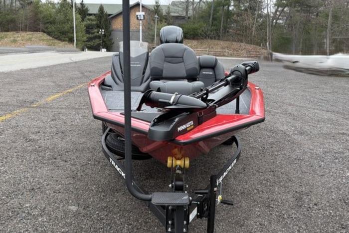 2026 Tracker Pro Team 175 boat, red, parked on gravel, featuring Minn Kota trolling motor.