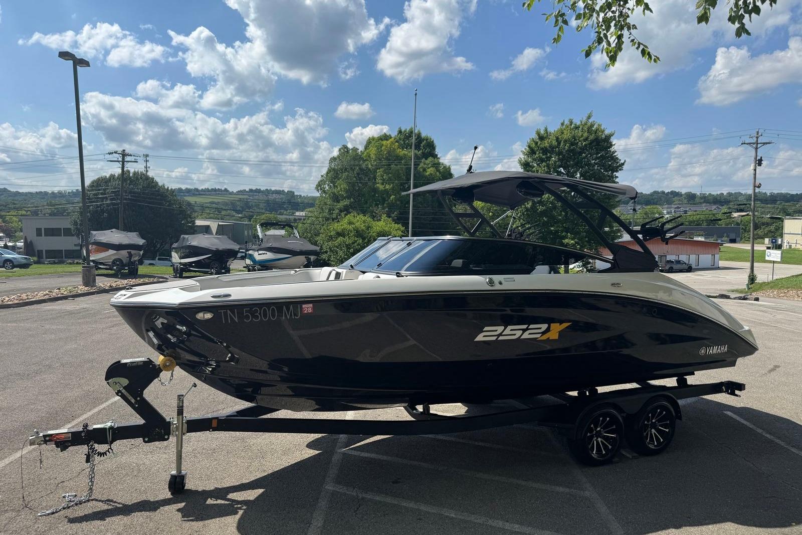 2023 Yamaha Boats 252XE on trailer under a sunny sky in a parking lot.
