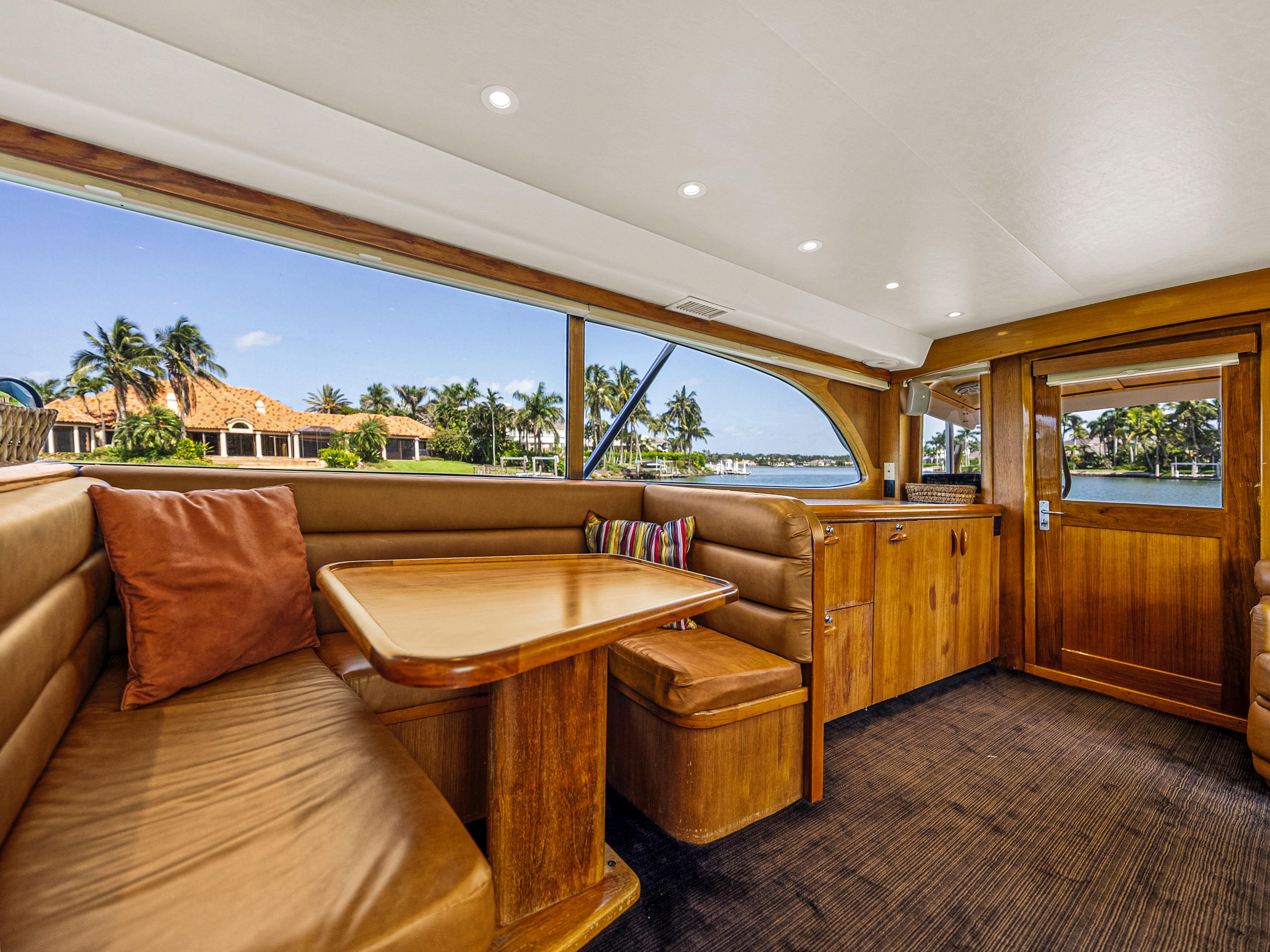 Interior of 1990 Buddy Davis 61 Convertible yacht with wooden furnishings and waterfront view.