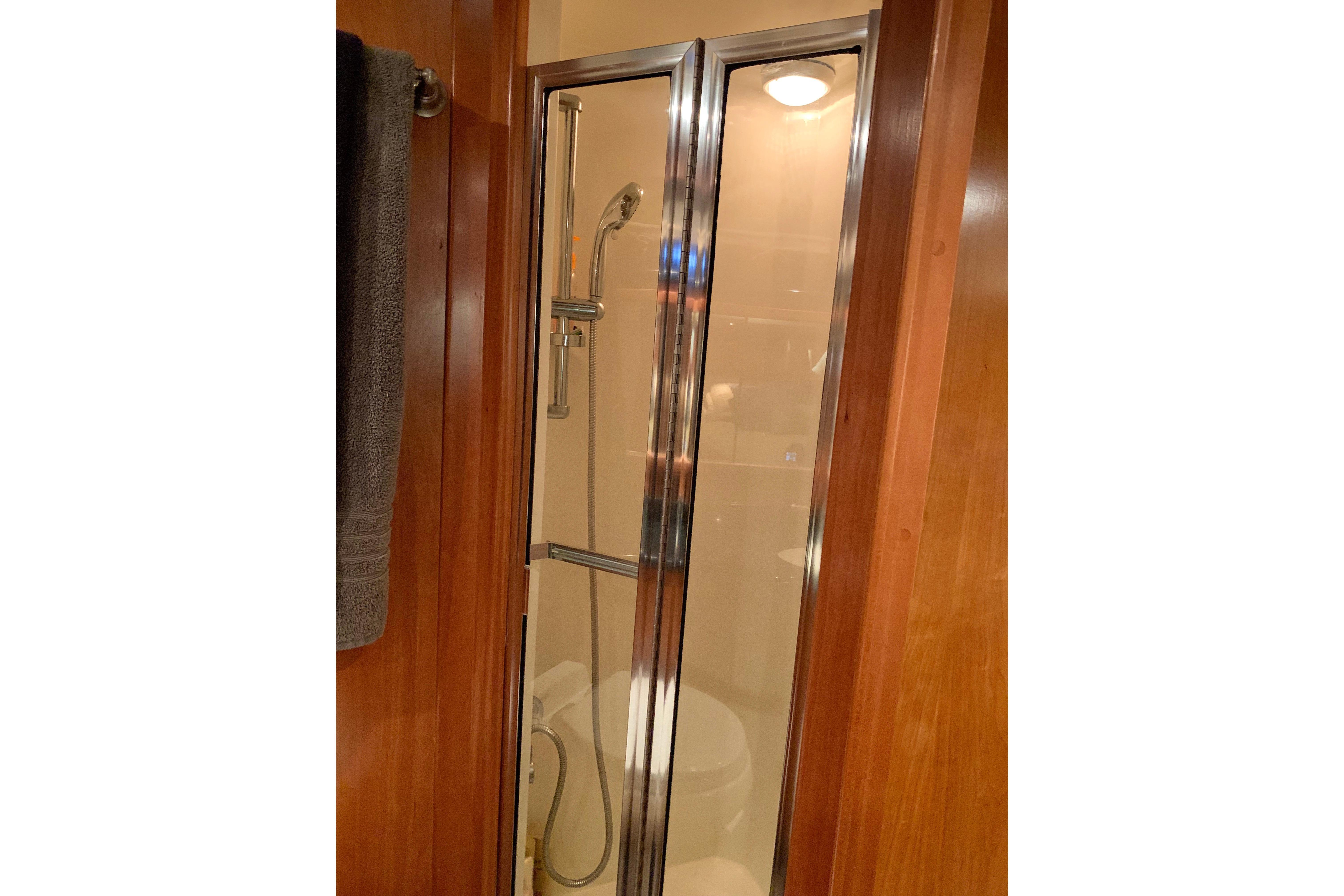 Shower area in 2007 Navigator 5100 yacht with glass door and wooden paneling.