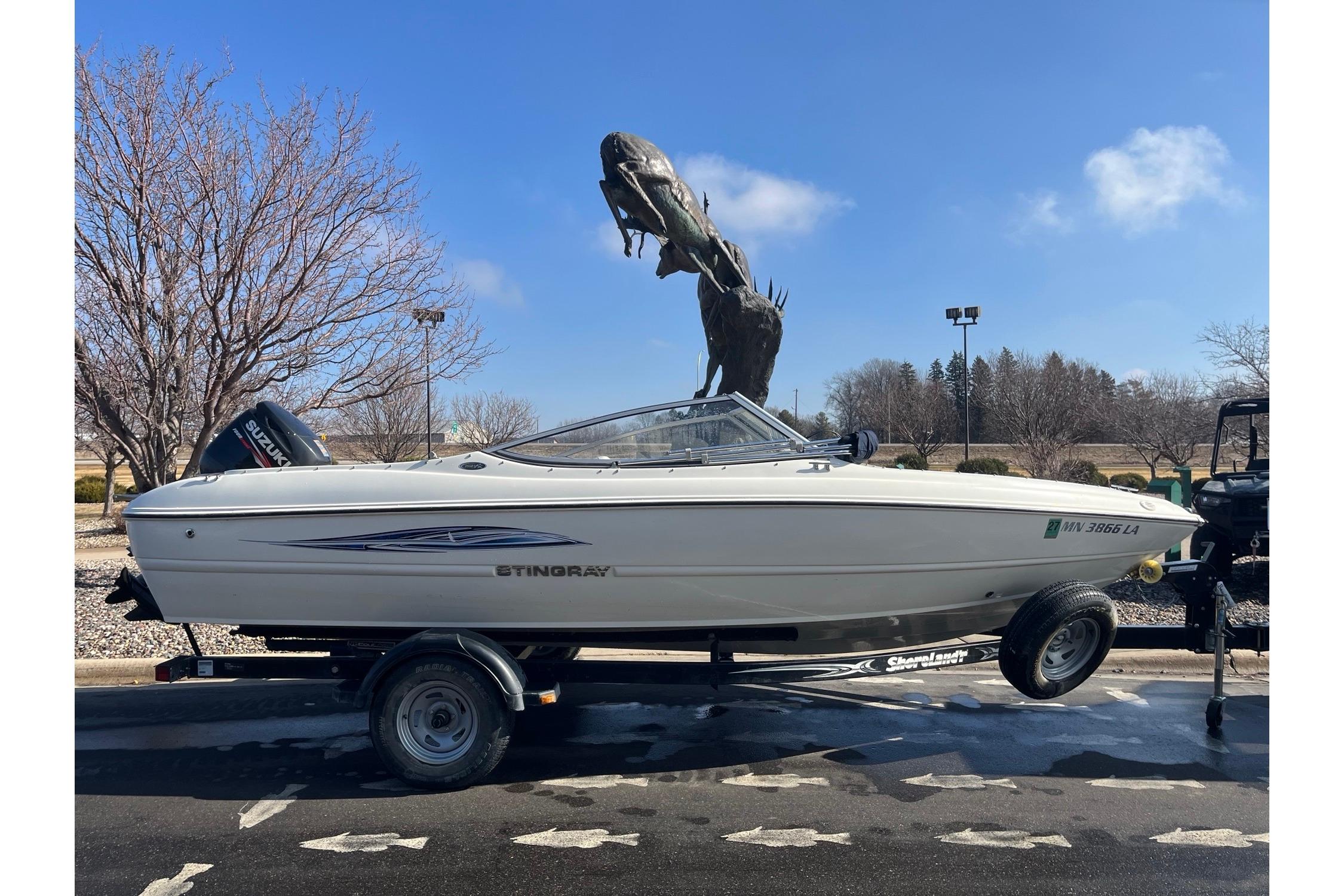 2013 Stingray 191 RX boat on trailer, parked near large outdoor sculpture.