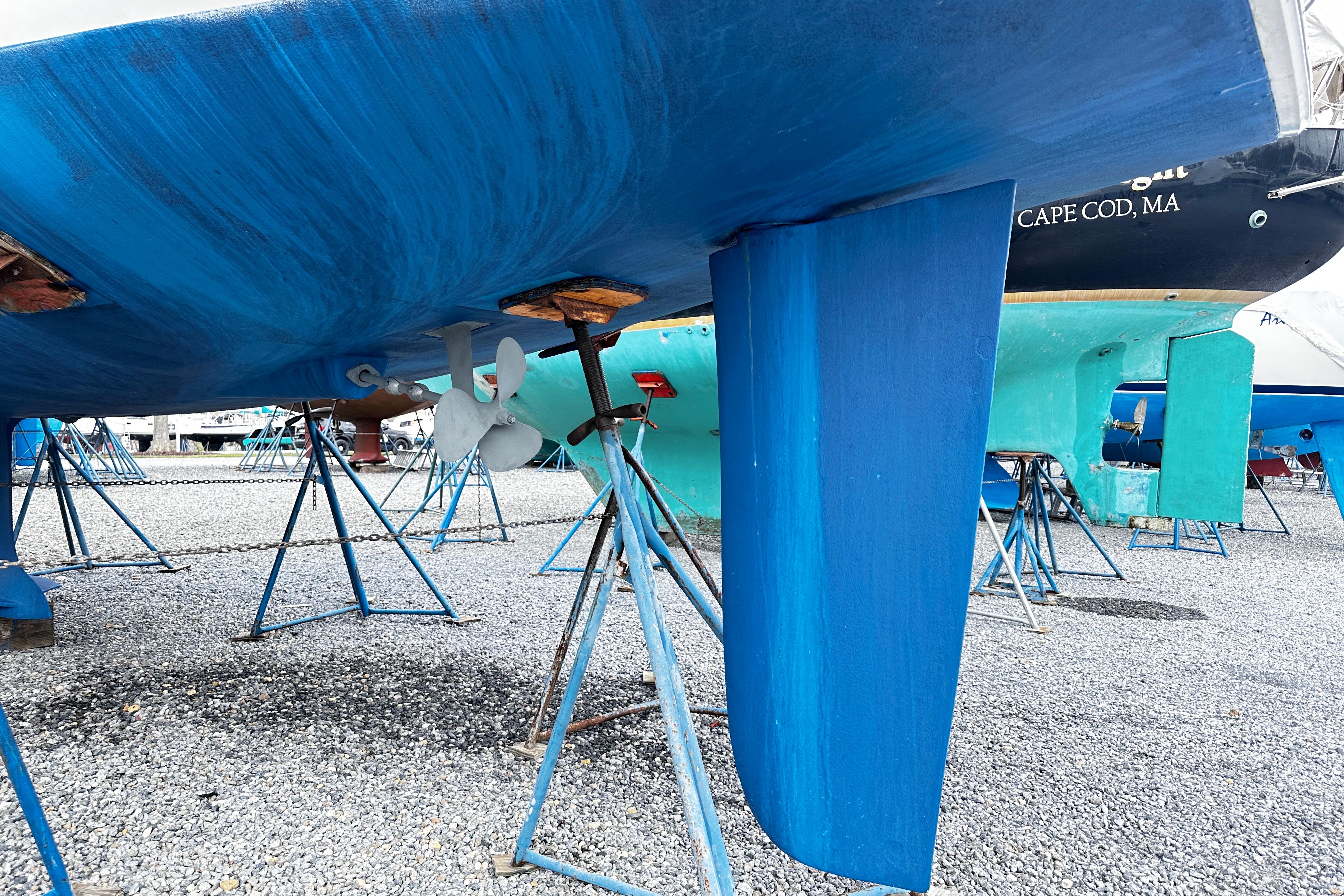 Blue hull of a 2004 Hunter 33 sailboat on stands in a boatyard.