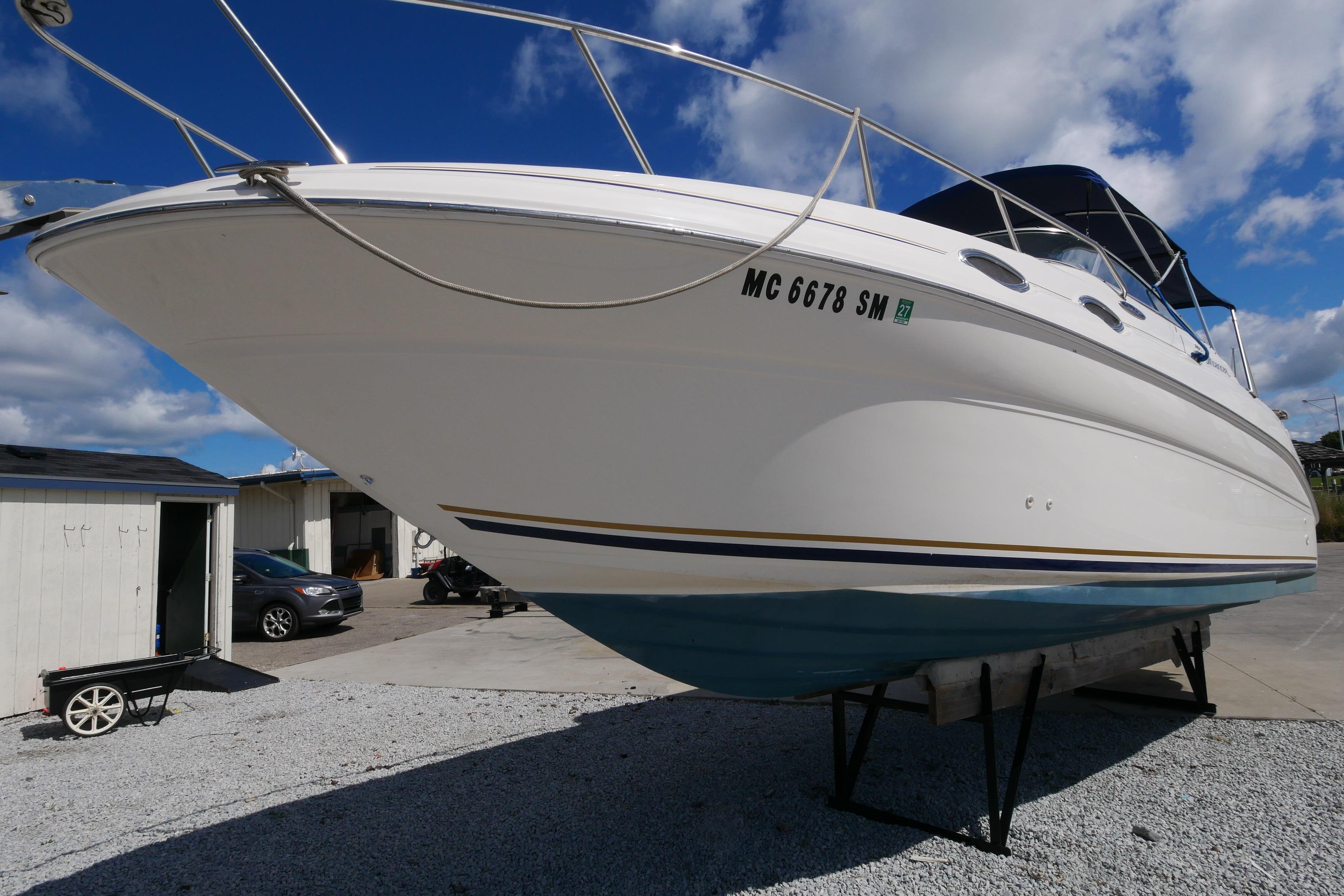 2003 Sea Ray 260 Sundancer boat on dry dock under blue sky.