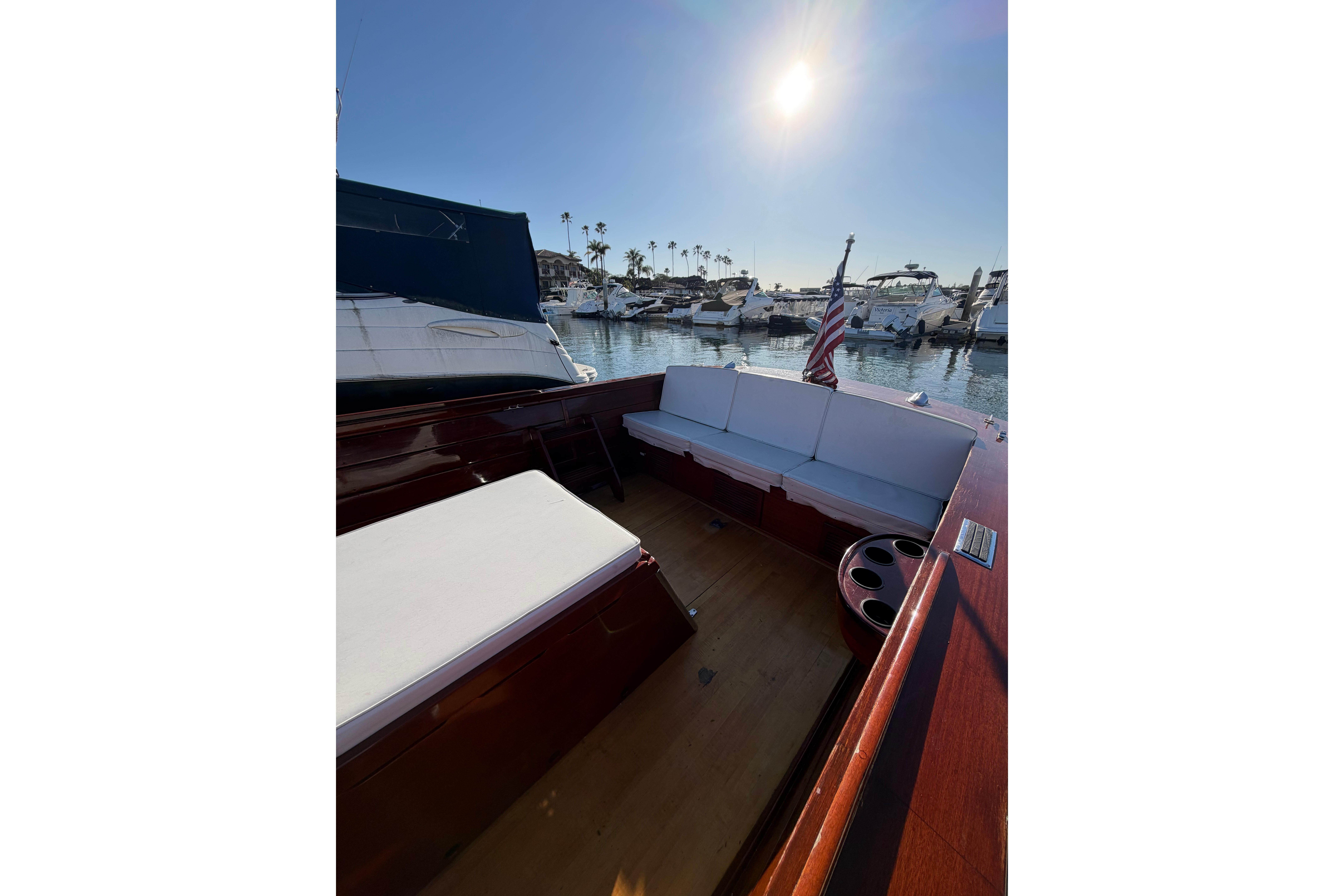 1964 Lyman 25 Sleeper boat interior with white seating, docked in sunny marina.
