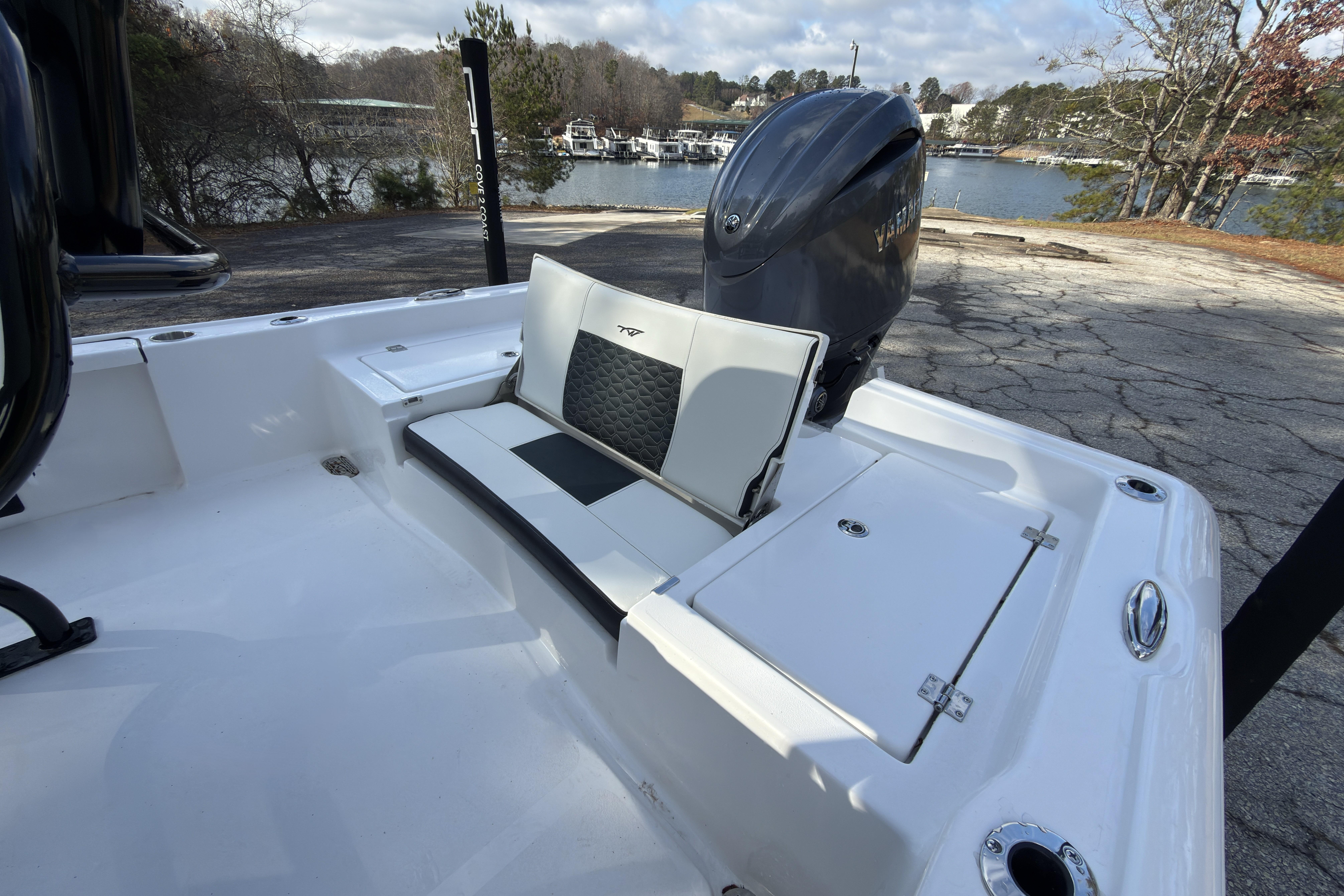 2026 Tidewater 2210 Carolina Bay boat interior with seating and engine, near a scenic lake.