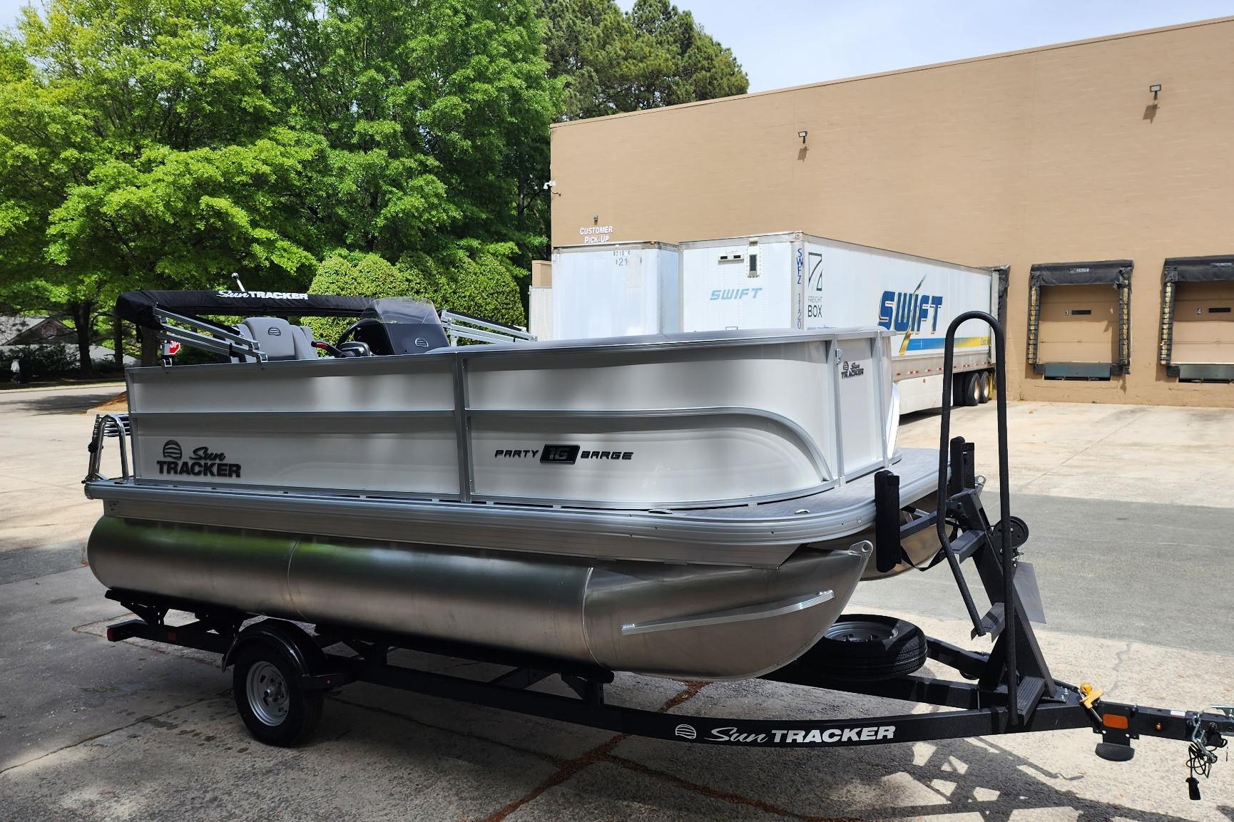 2026 Sun Tracker Party Barge 16 DLX pontoon boat on trailer, parked outdoors.