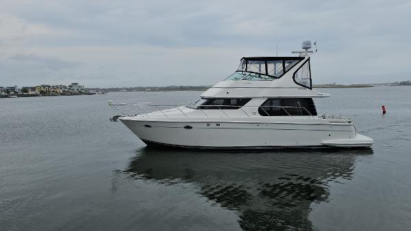 2000 Carver 450 Voyager Pilothouse yacht on calm water, overcast sky.