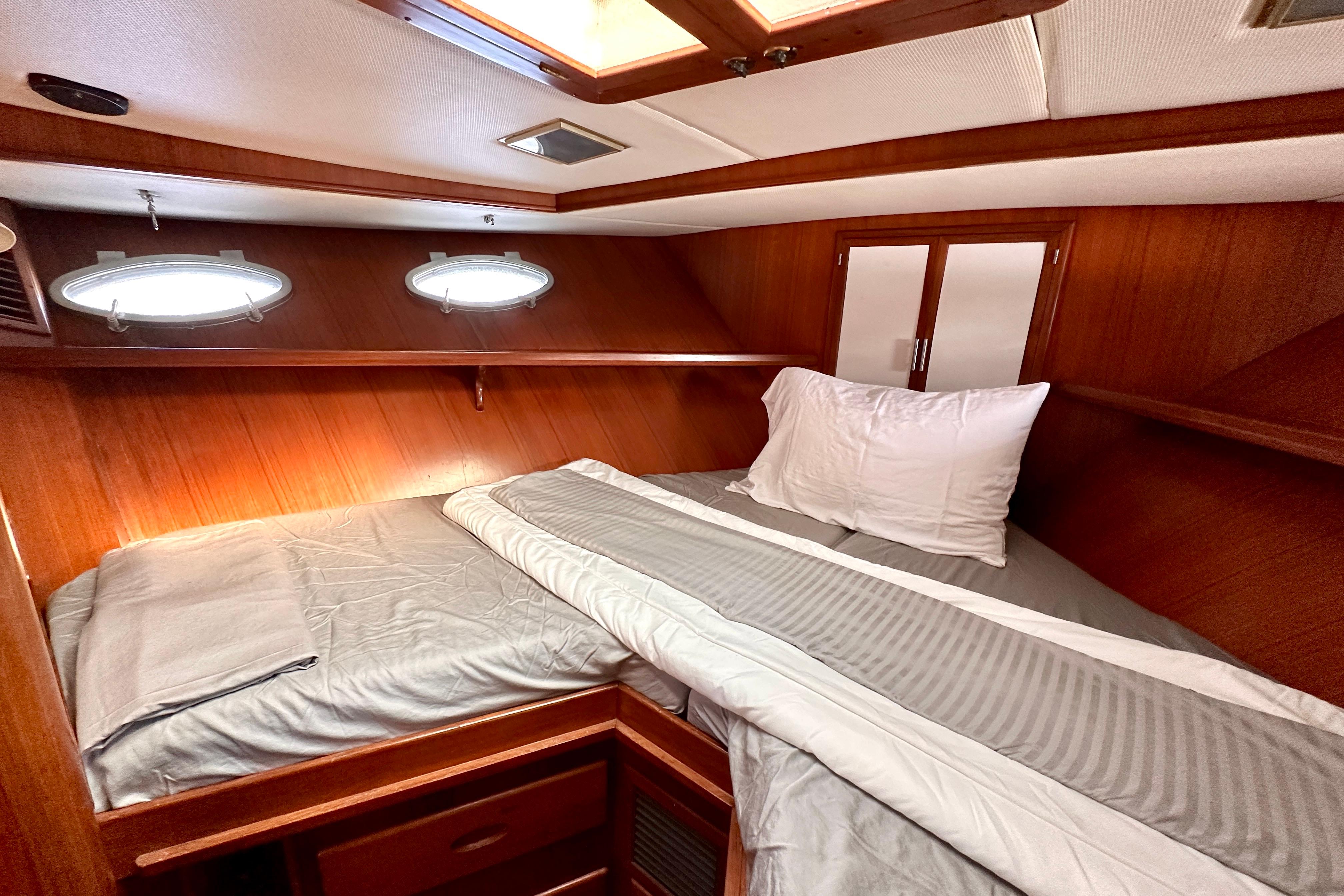 Cozy cabin interior of 1987 Marine Trader 47 Tradewinds yacht with wood paneling and bedding.